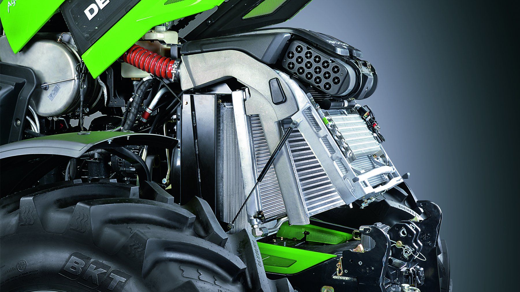 Close-up of a green and black ATV's front showing the radiator and suspension components.
