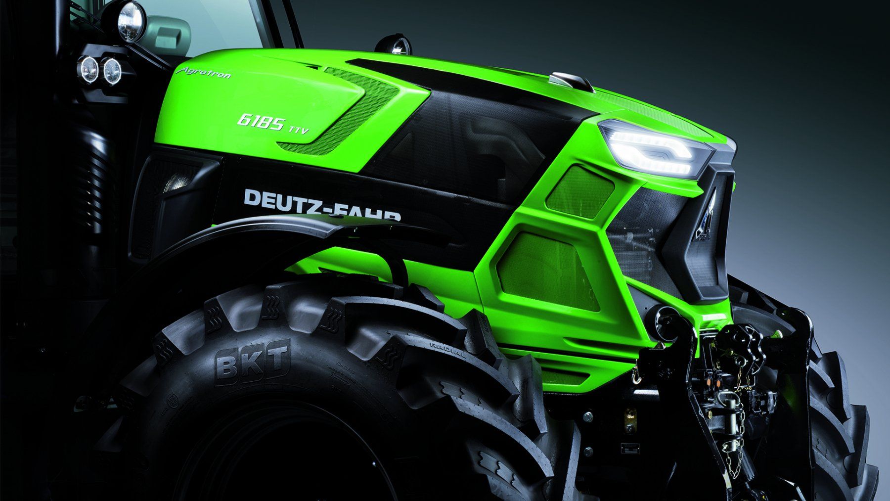 Green and black Deutz-Fahr tractor with large tires, angled front, and bright headlights.