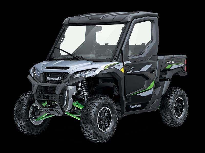 Kawasaki utility vehicle, gray and black with green accents, large tires, enclosed cabin, outdoor setting.