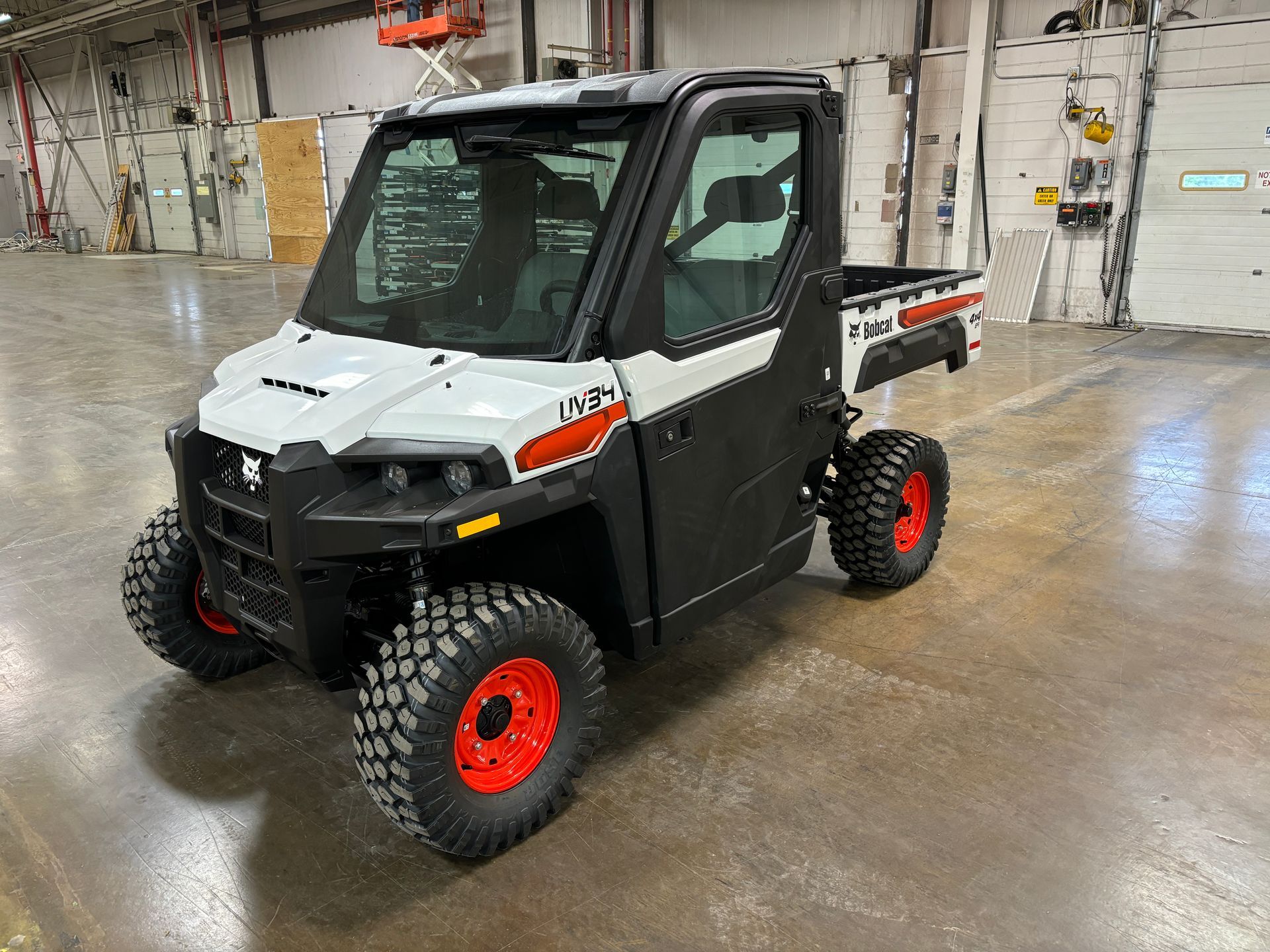 White and black Bobcat utility vehicle with red wheels in a warehouse.