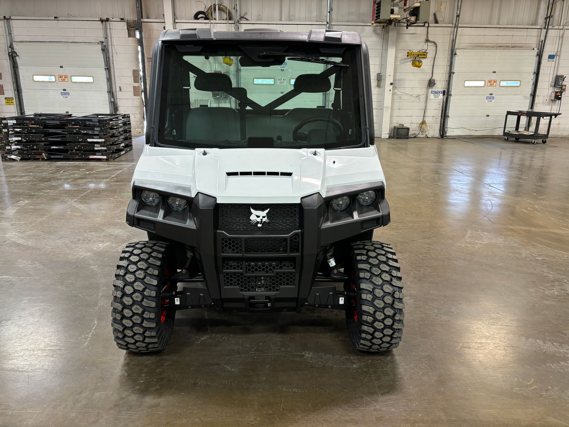 White and black Bobcat utility vehicle parked inside a warehouse.