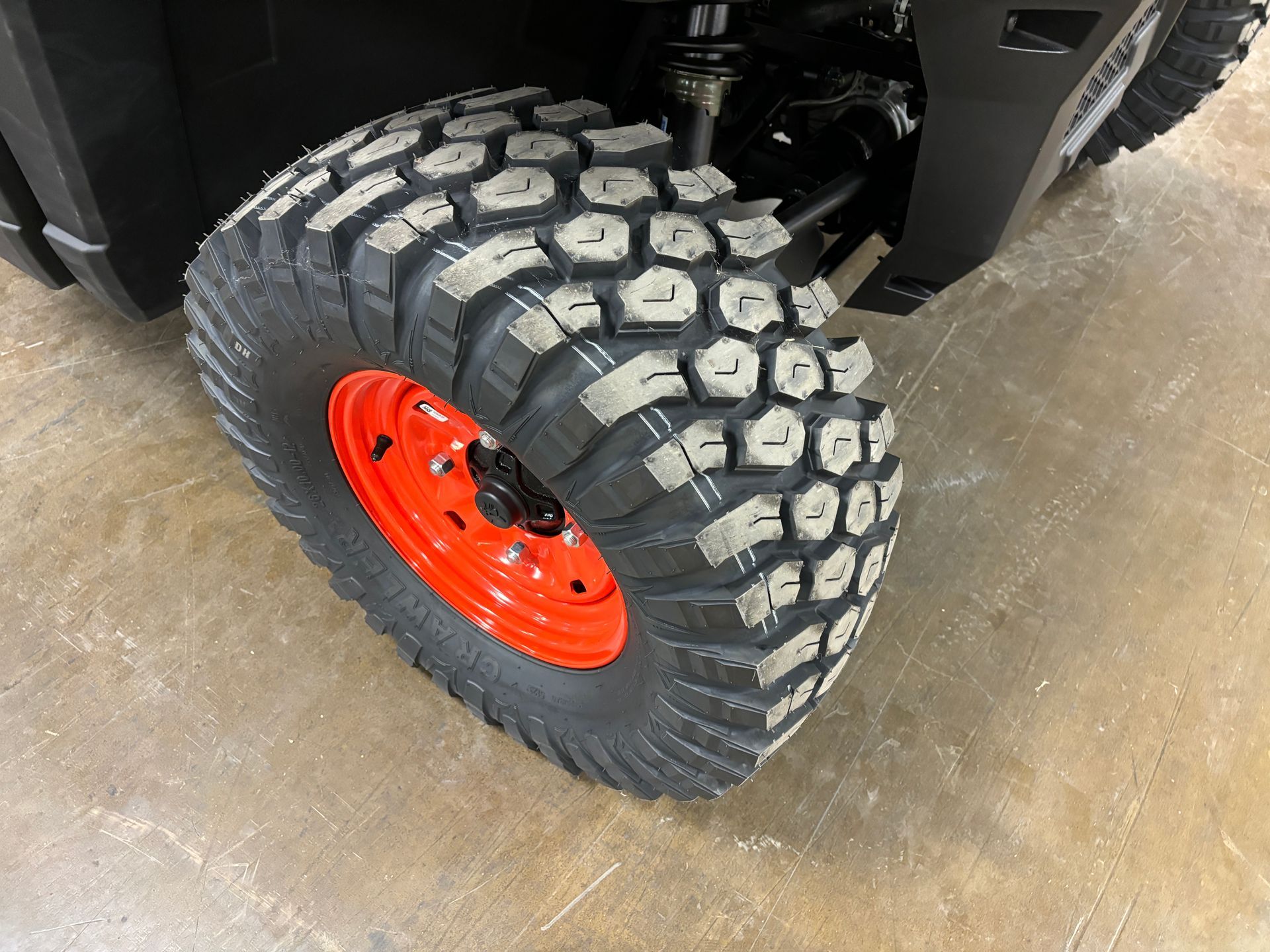Close-up of an ATV wheel with a large, patterned tire and an orange rim.