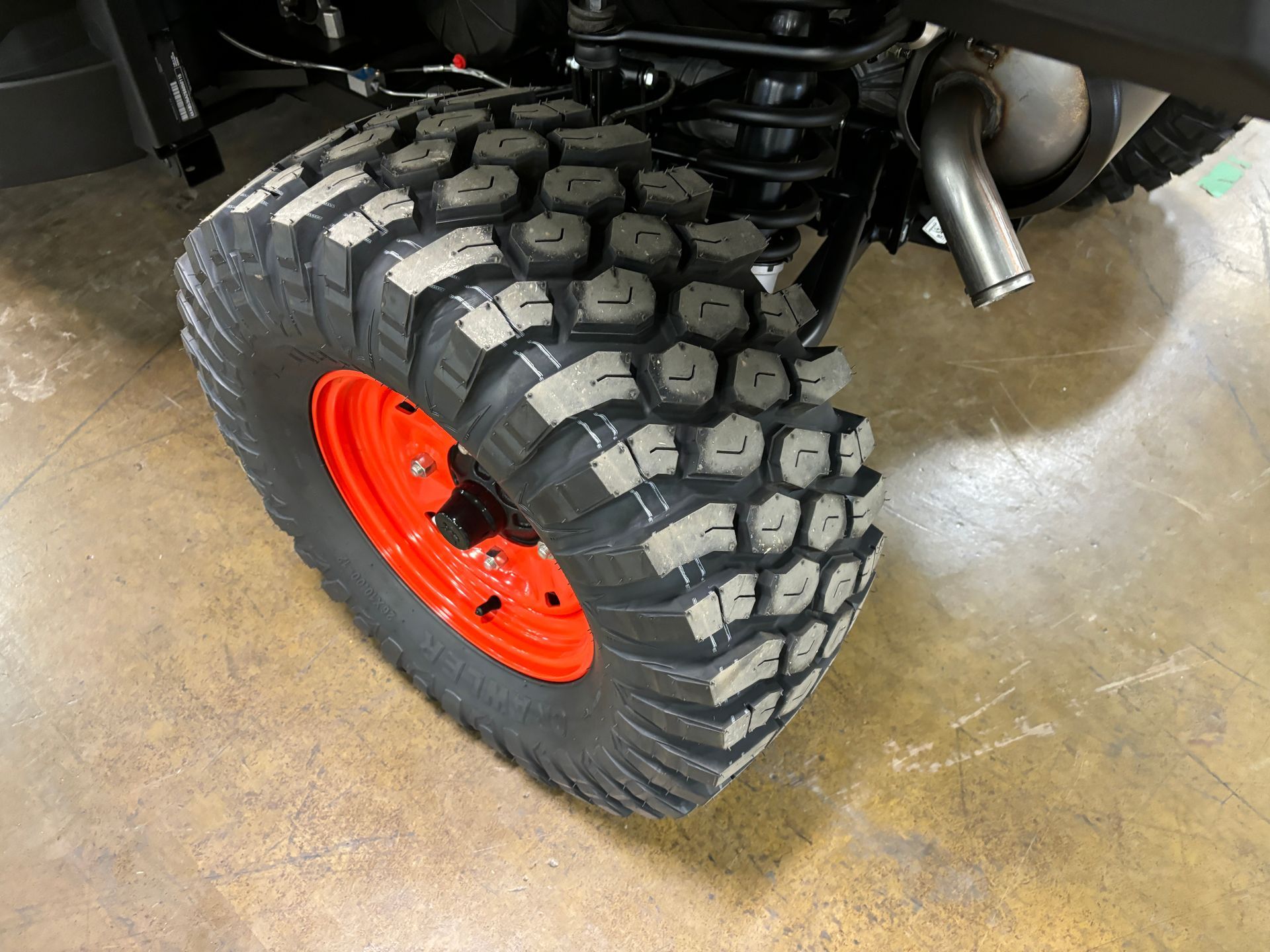 Orange wheel with a large, textured tire on a vehicle.