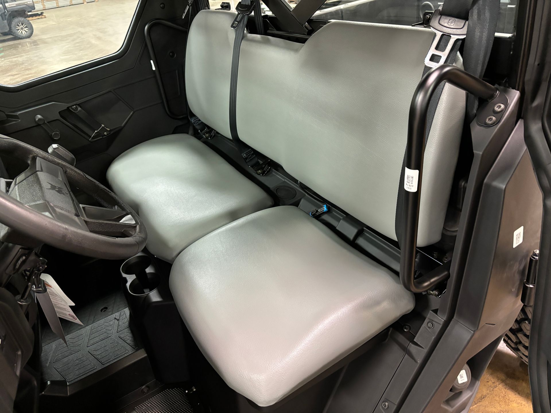 Gray seats in a utility vehicle, with a steering wheel and black interior.