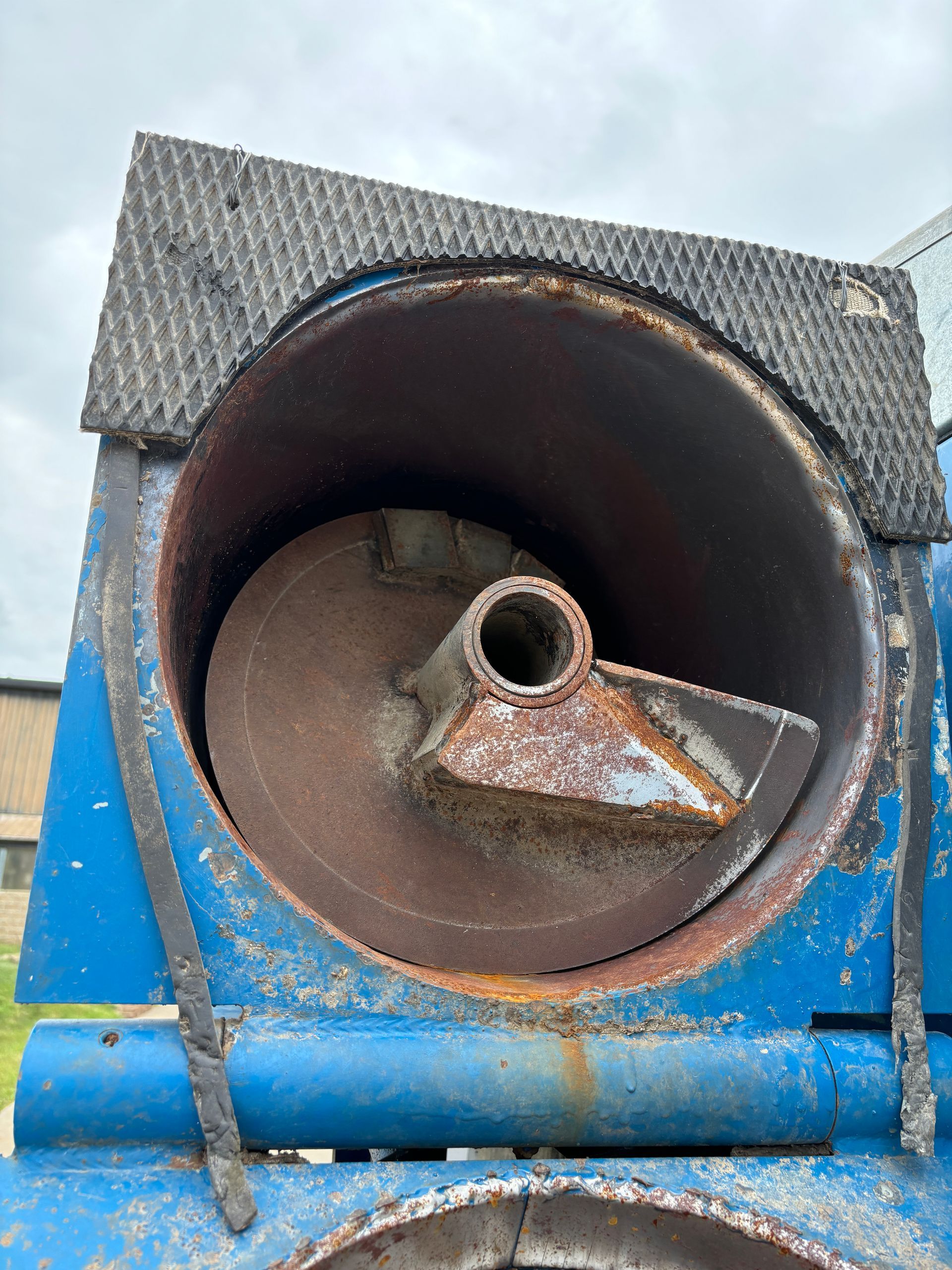 Rusty auger inside a blue metal container with a black textured top.