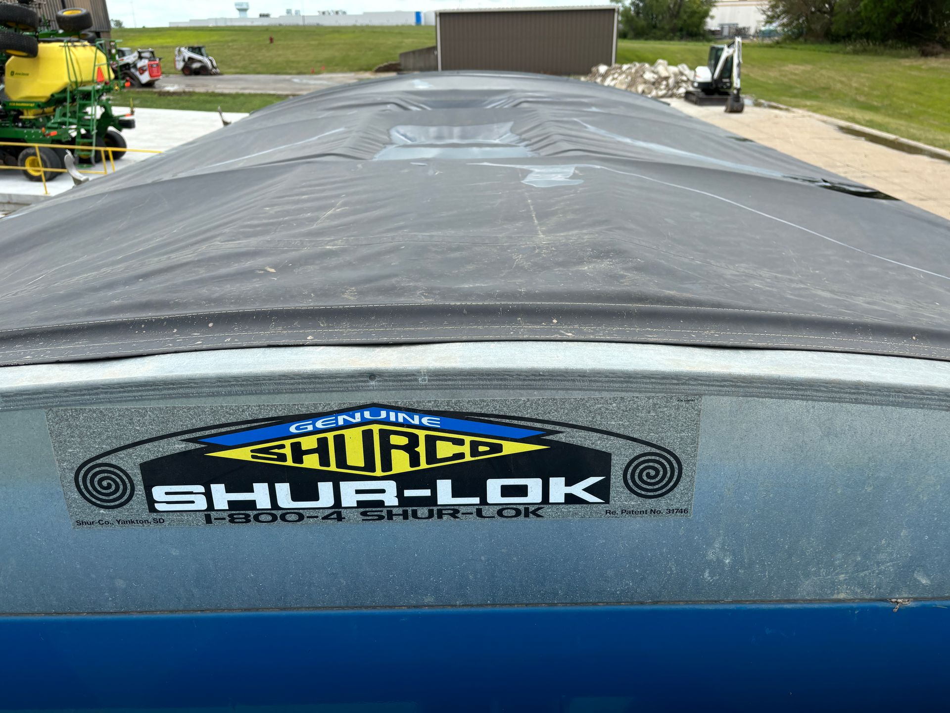 Close-up of a blue Shur-Lok trailer with a black tarp cover. The logo is prominently displayed.