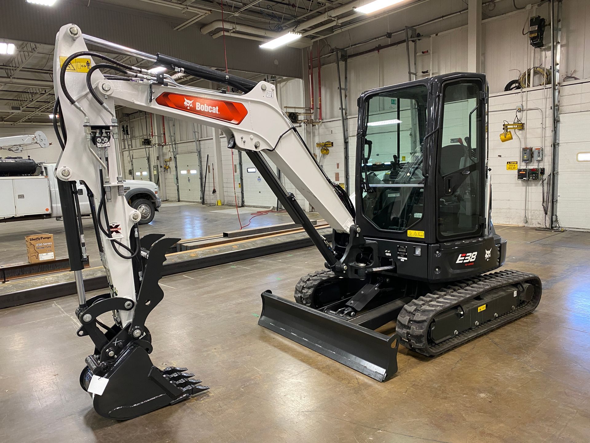 Bobcat E42 mini excavator in a large warehouse. White and black, with a black bucket.