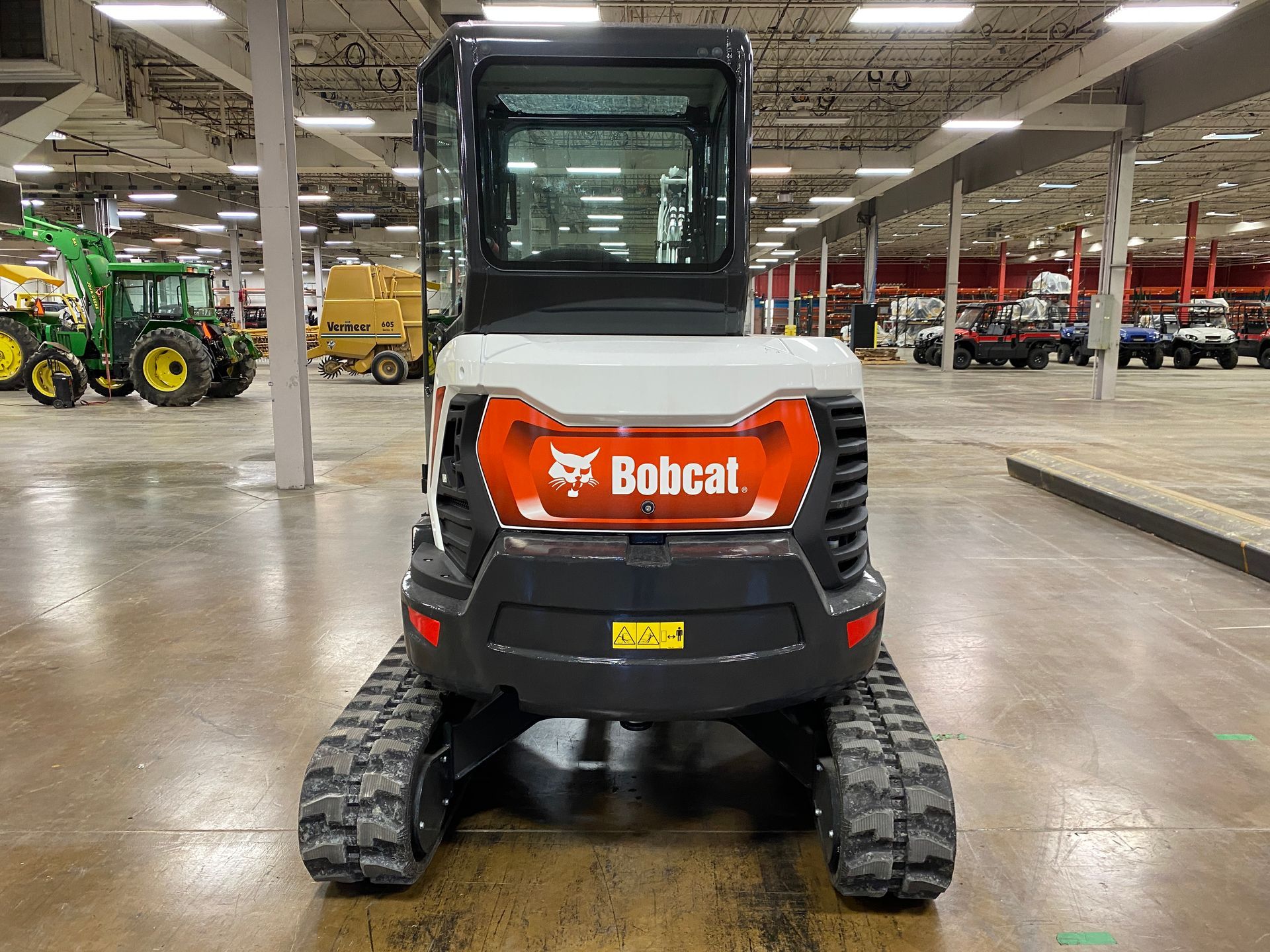 Bobcat compact excavator with orange and white details on tracks, indoors.