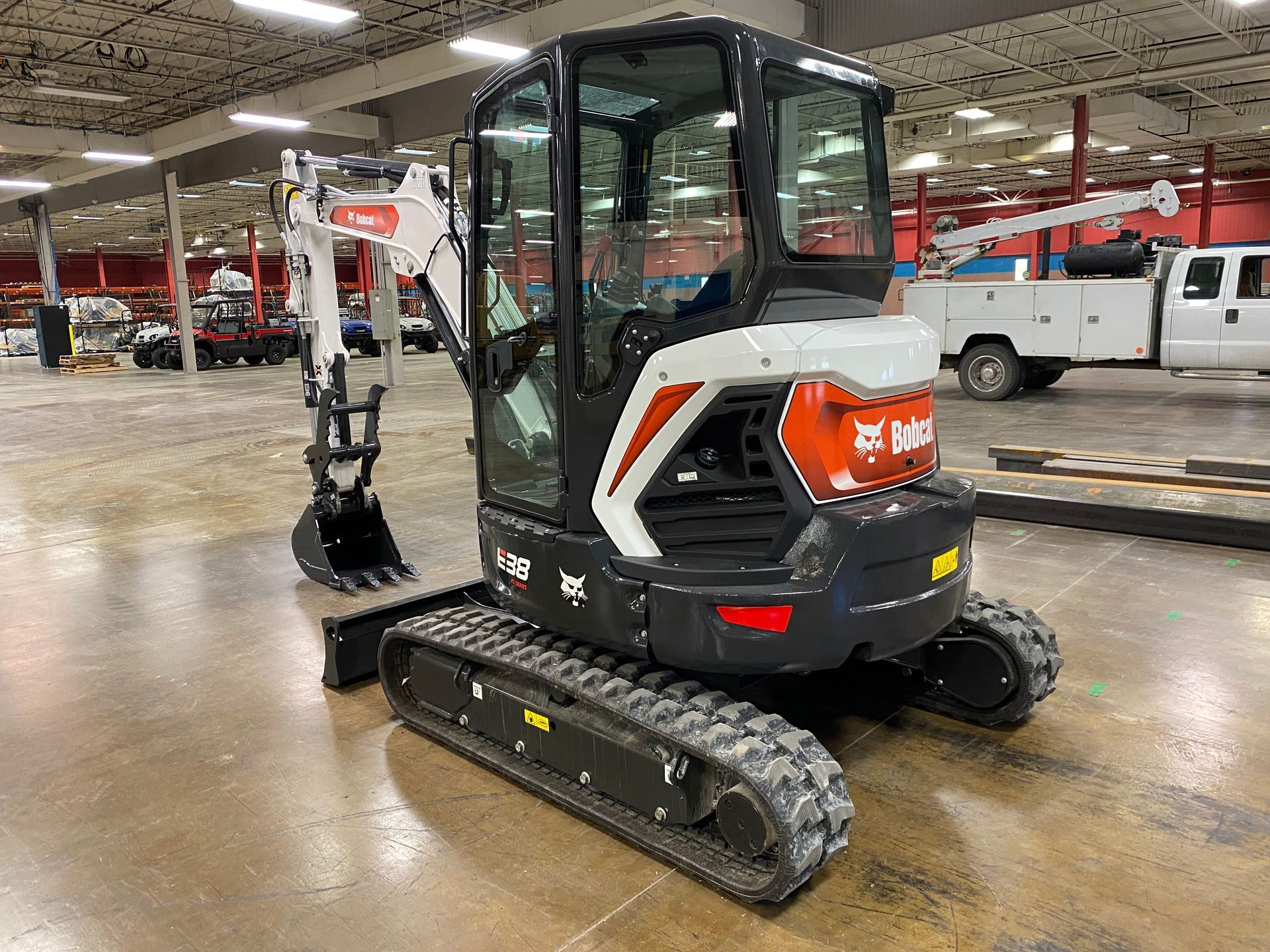 Bobcat E20 excavator on tracks, inside a building. Black, white, and orange.