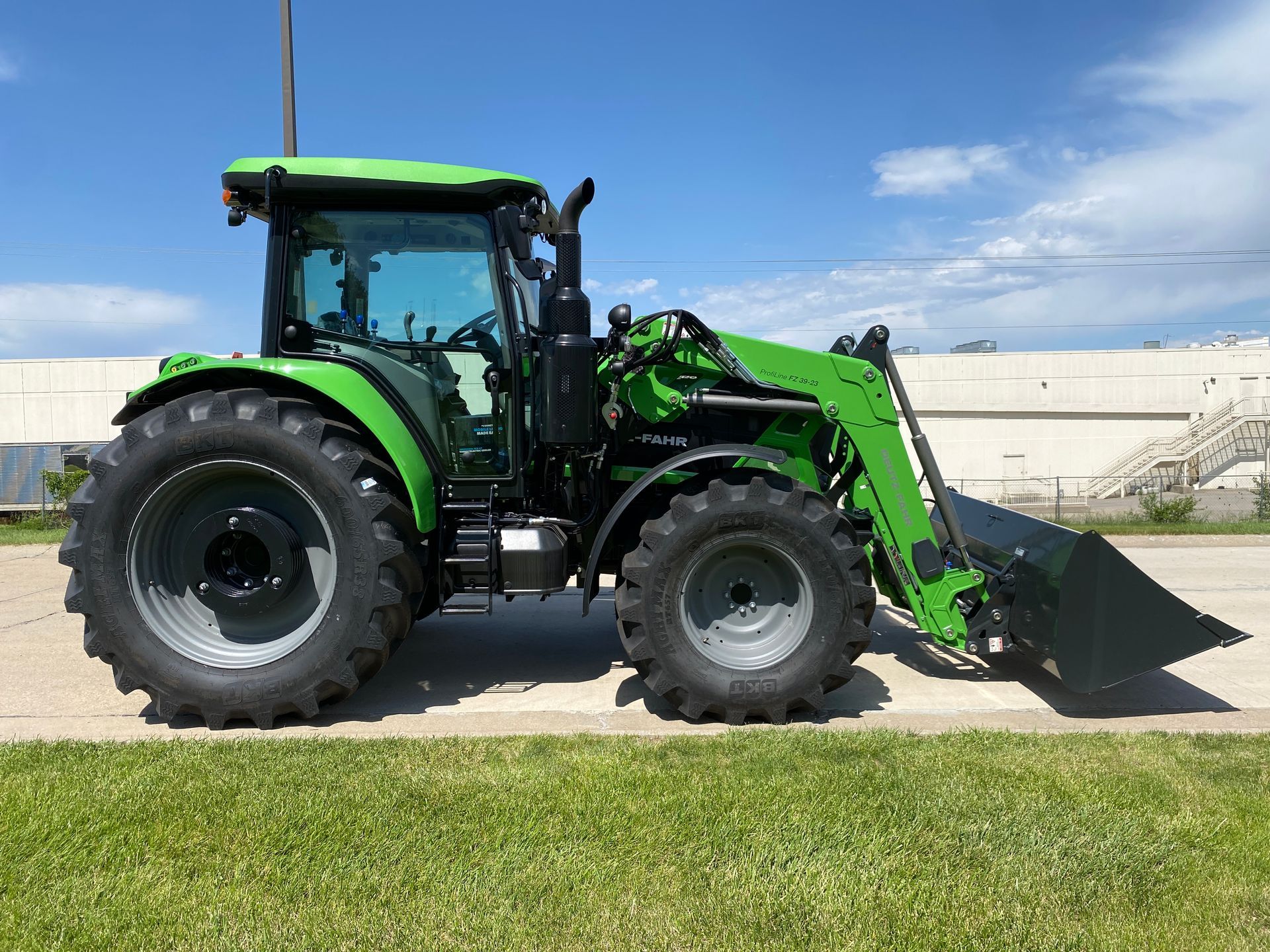Green tractor with front loader on grass.
