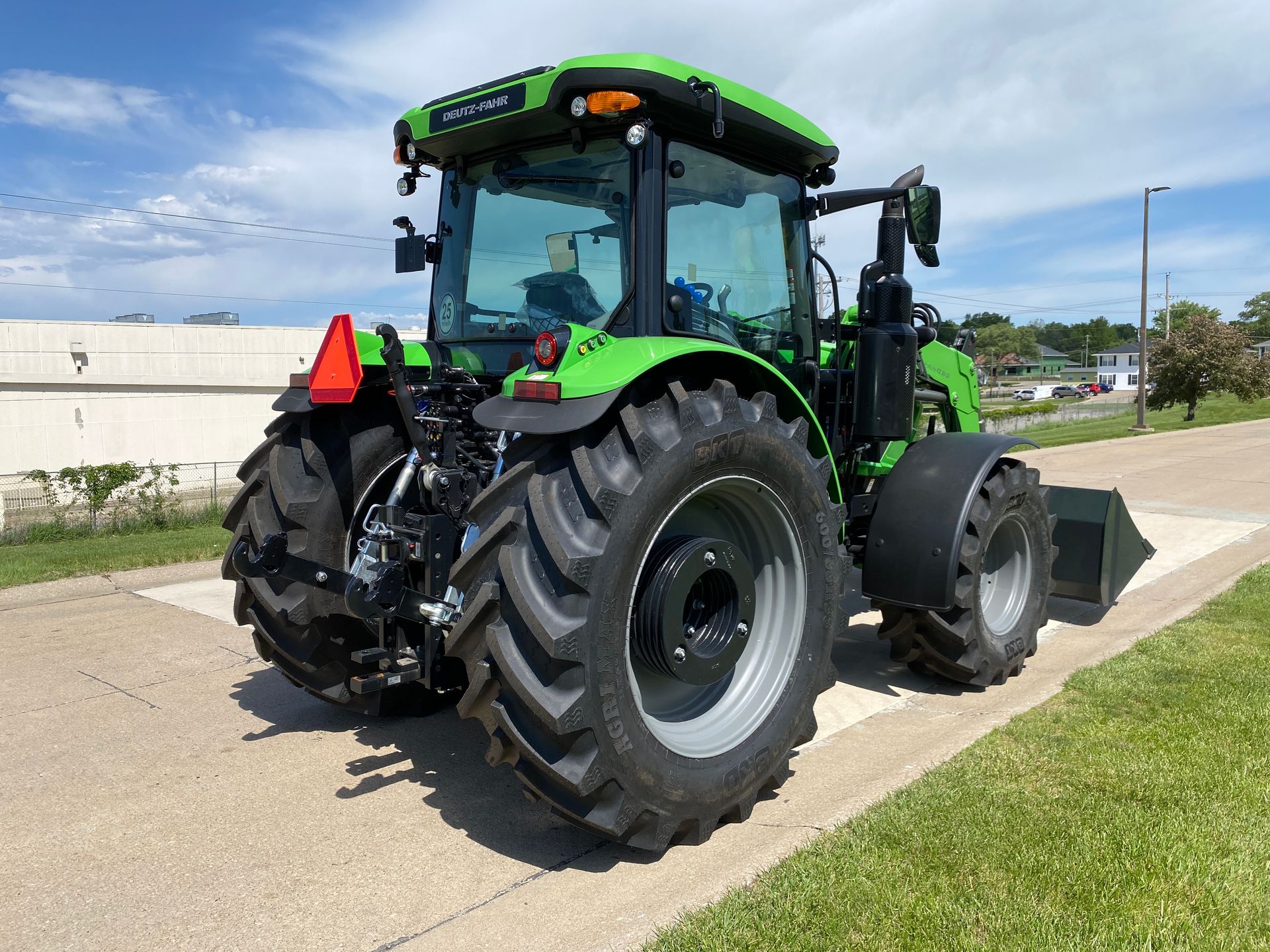Green tractor on pavement; sunny outdoor setting.