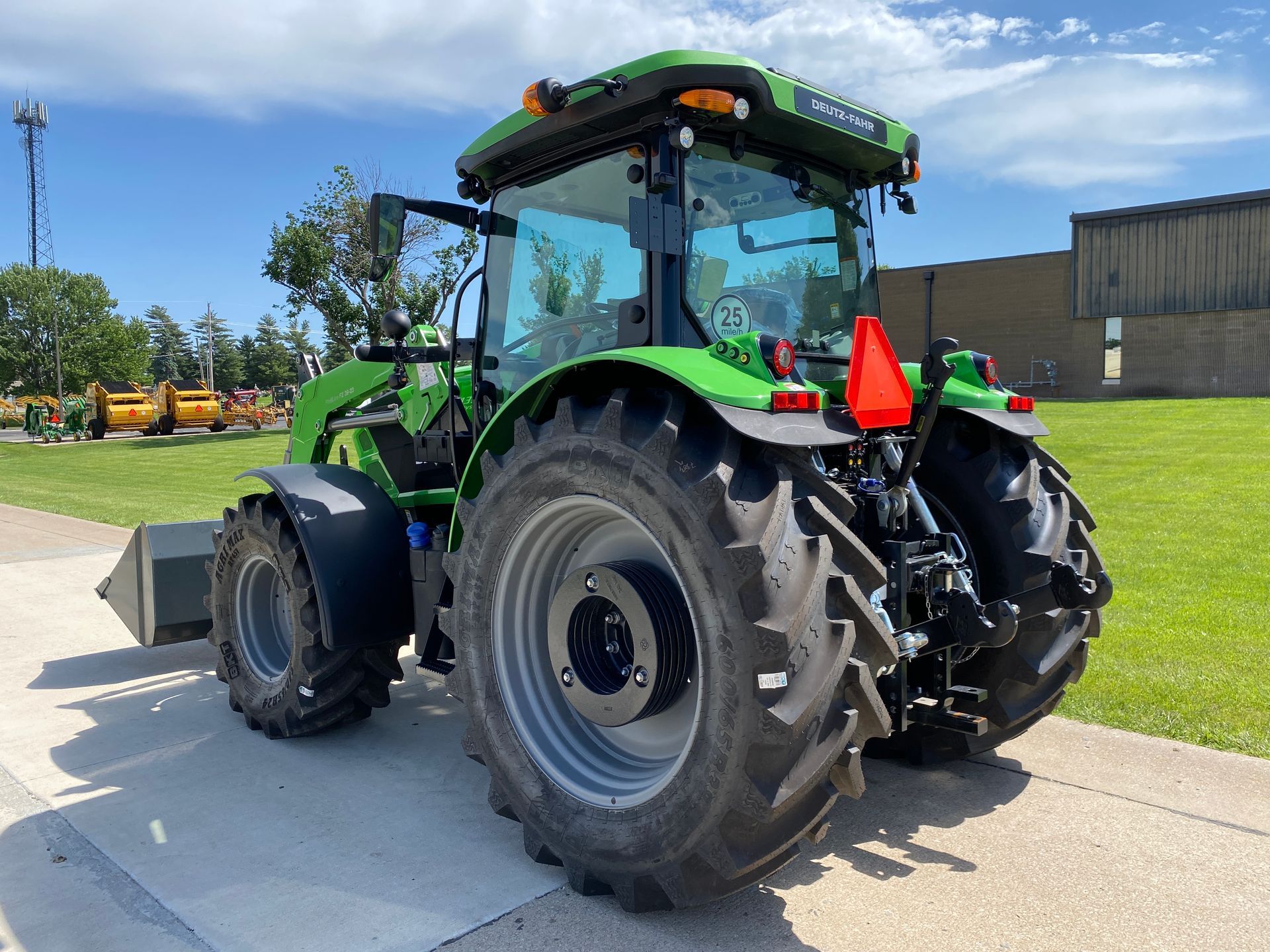 Green tractor on pavement; blue sky backdrop.