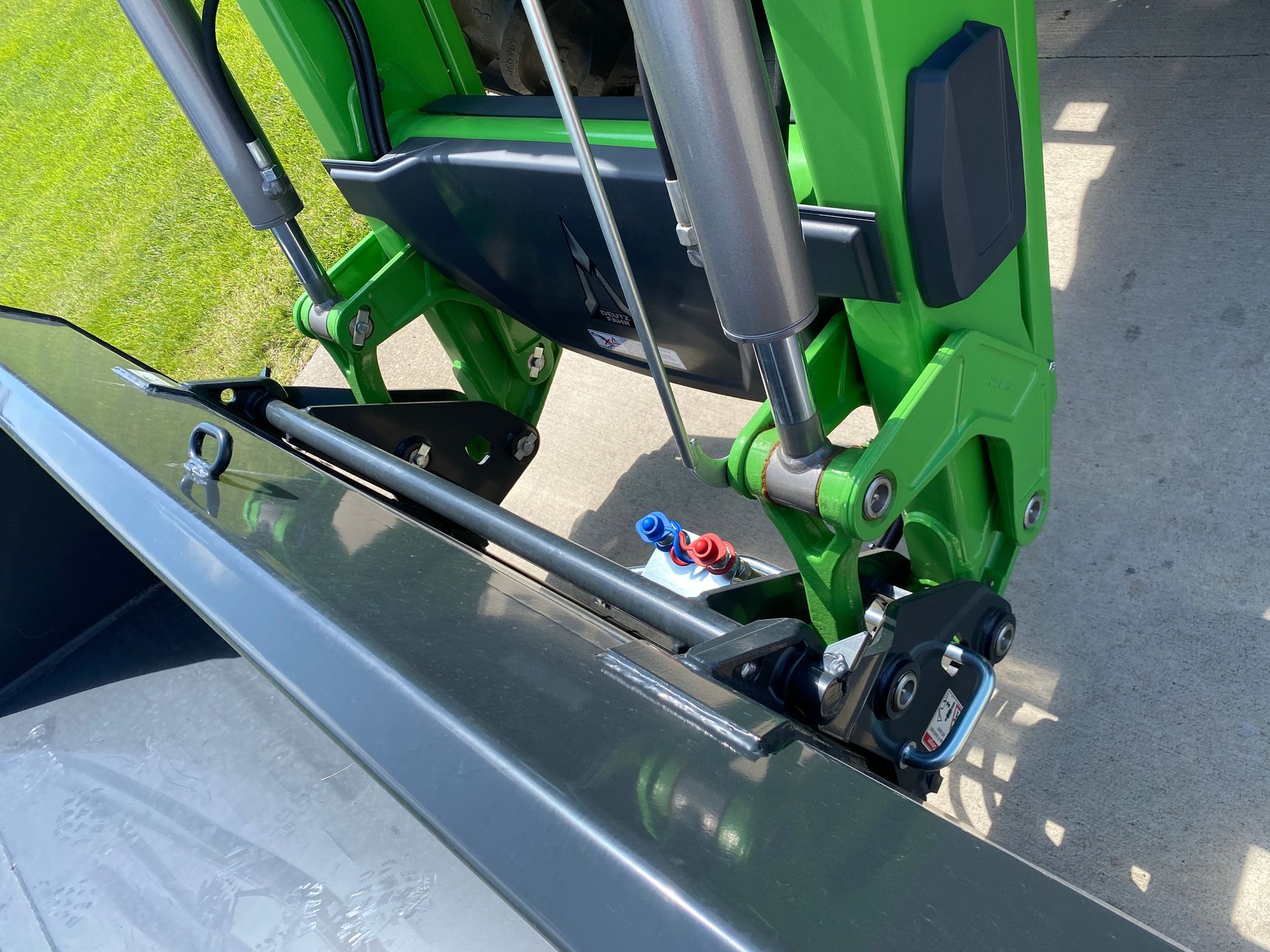 Green and black tractor bucket and lift mechanism detail.