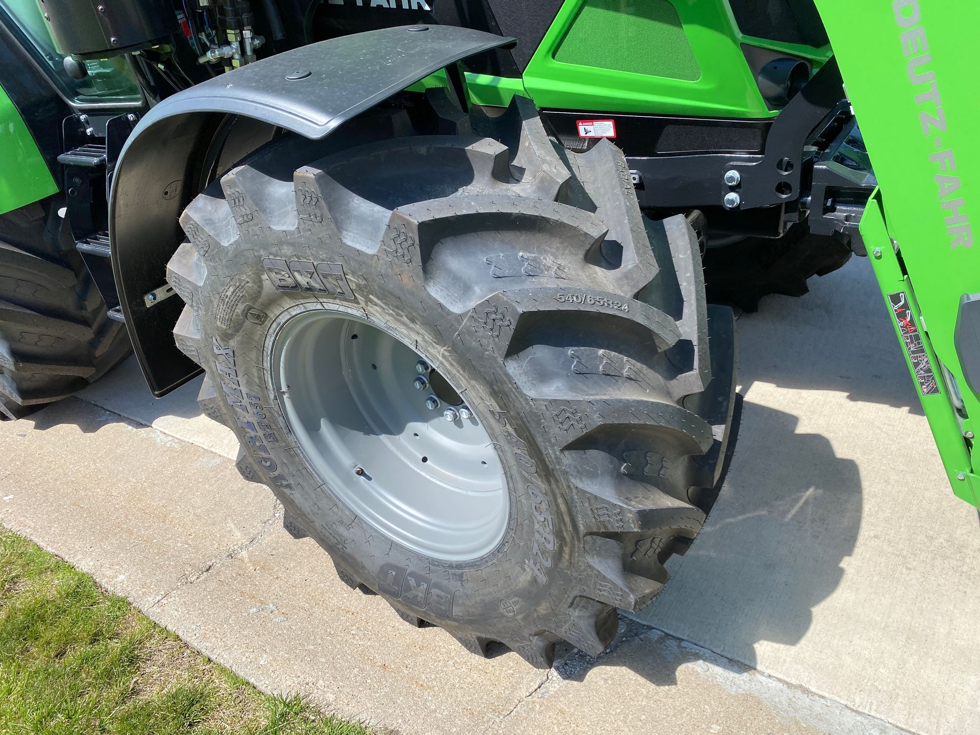 Green tractor tire and fender on concrete.