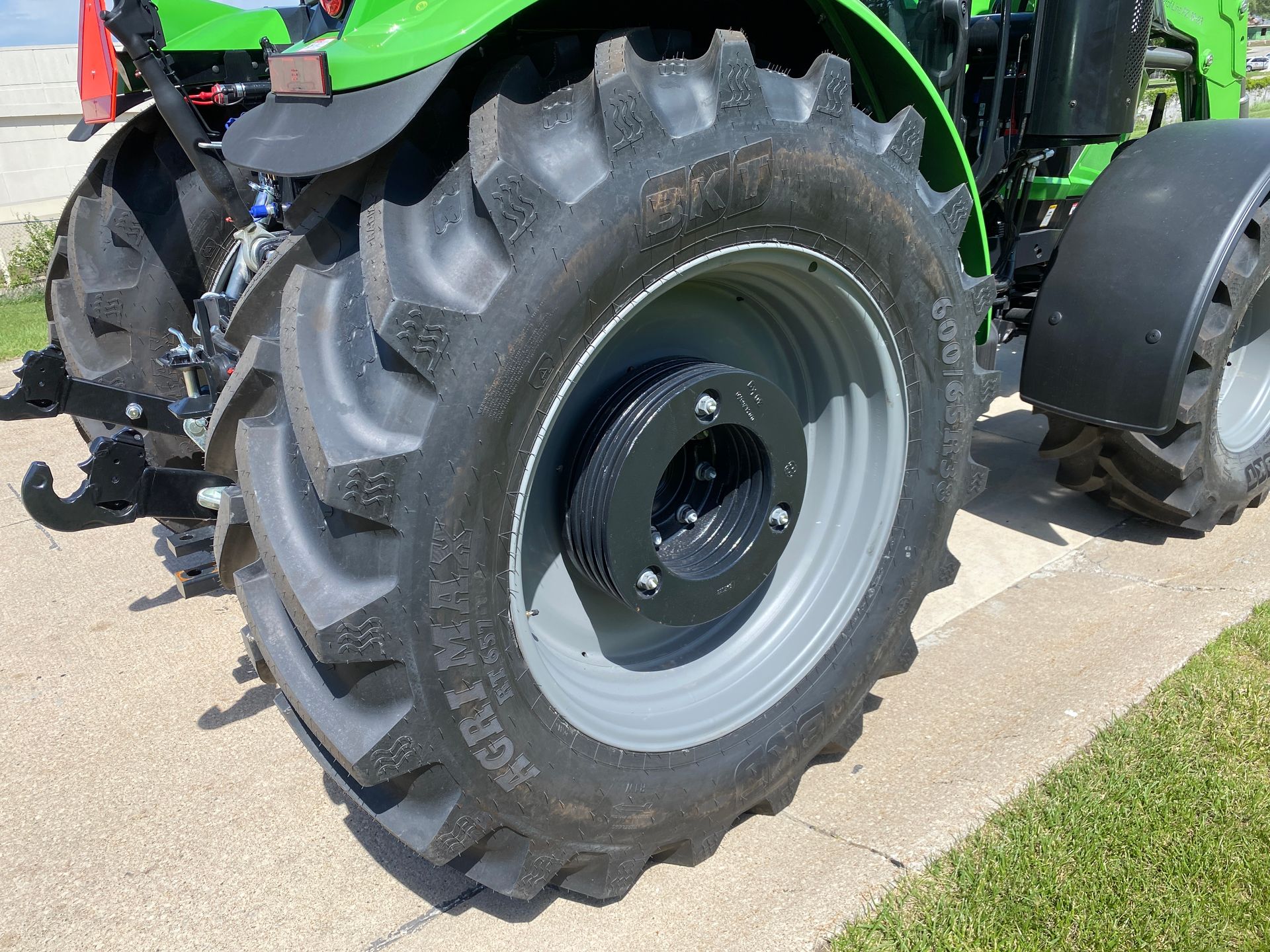 Close-up of a tractor's rear tire. The tire is black with deep treads, and the rim is gray.