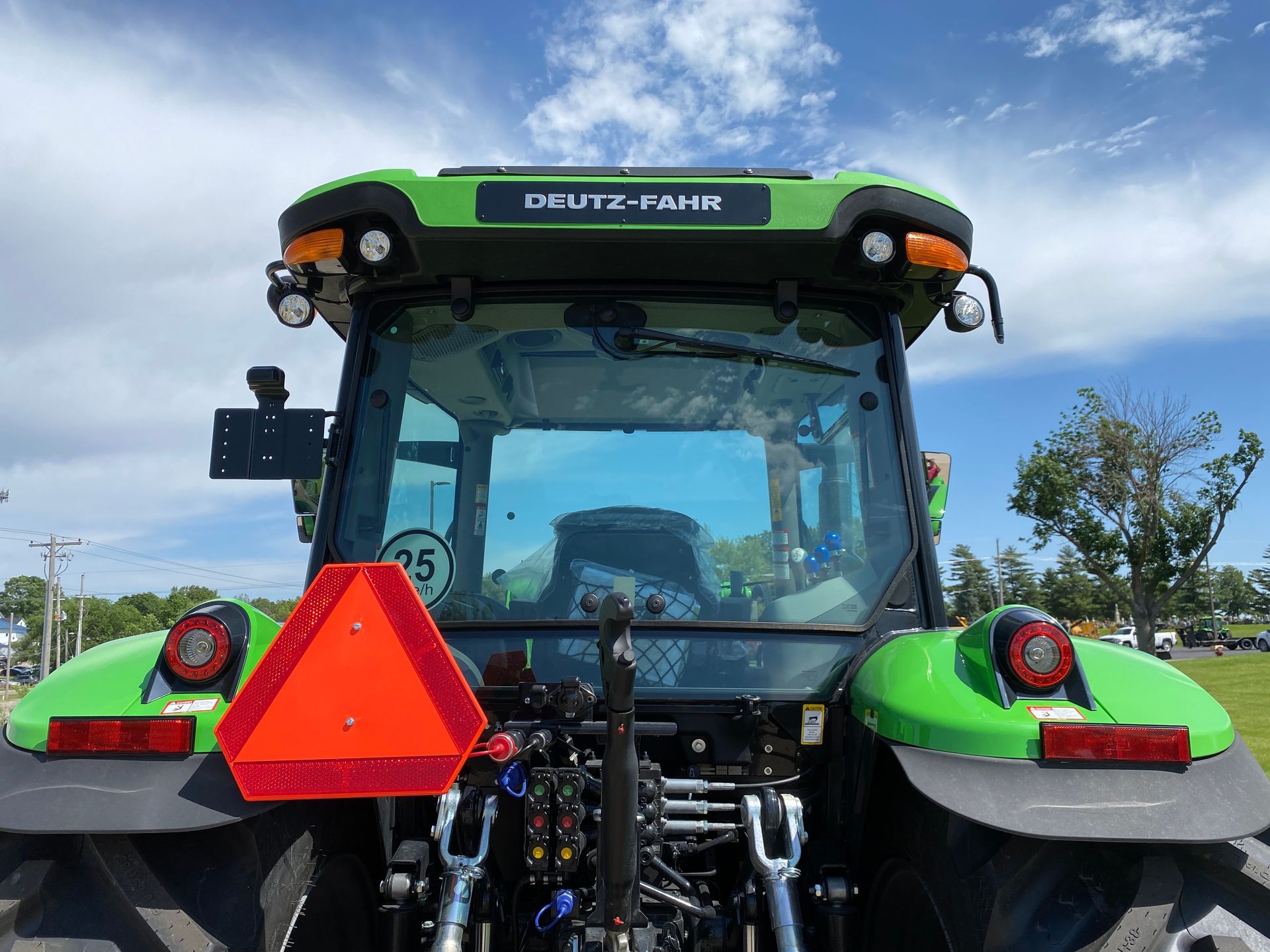 Rear view of a green and black Deutz-Fahr tractor with an orange triangle safety sign.