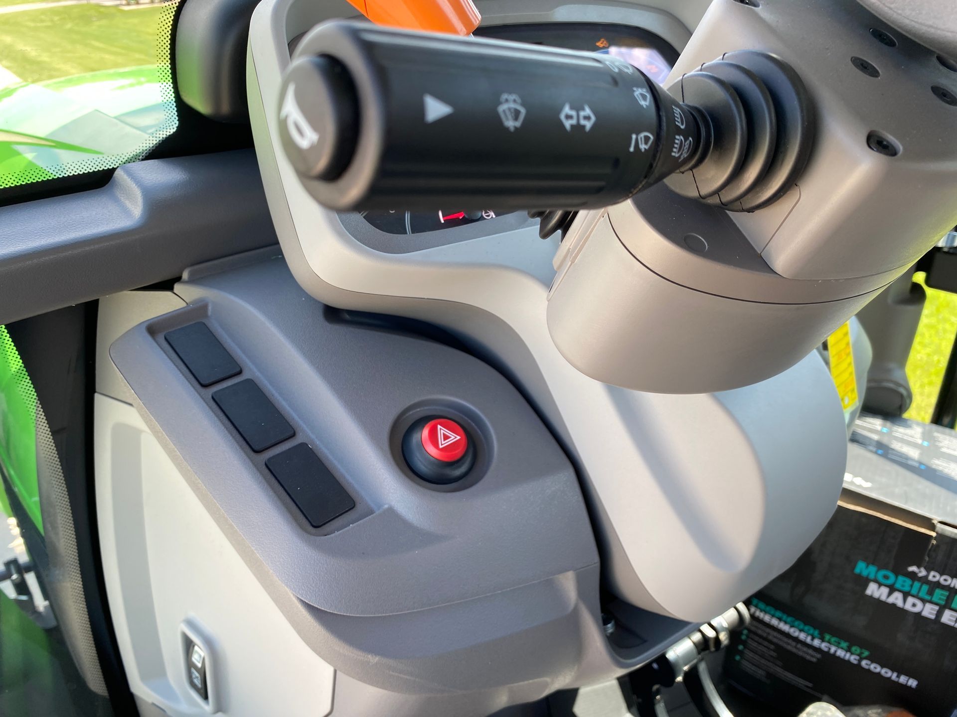 Close-up of tractor dashboard controls, including a hazard light button and a turn signal lever.