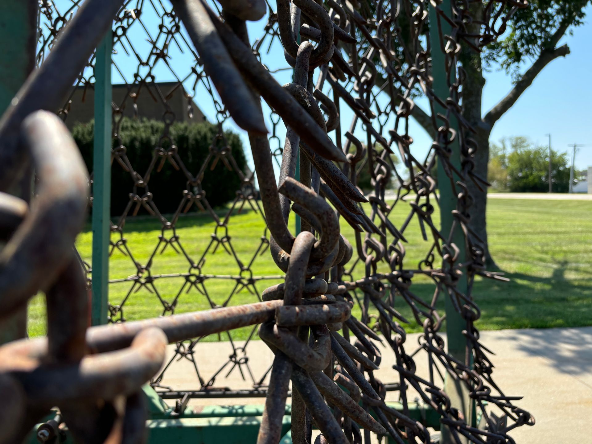 Close-up of a harrow, with a green grassy area and trees in the background.