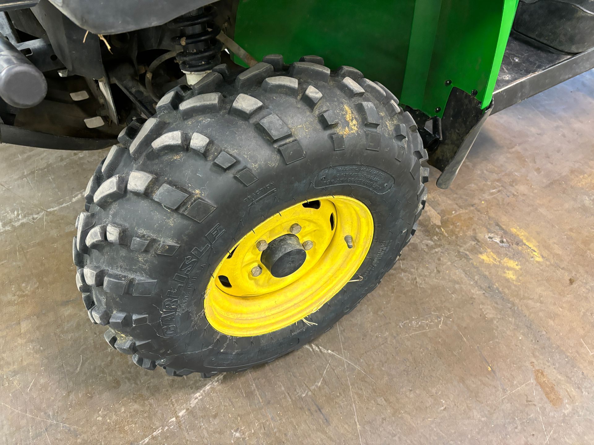 Yellow-rimmed, black-treaded tire on a green John Deere utility vehicle.