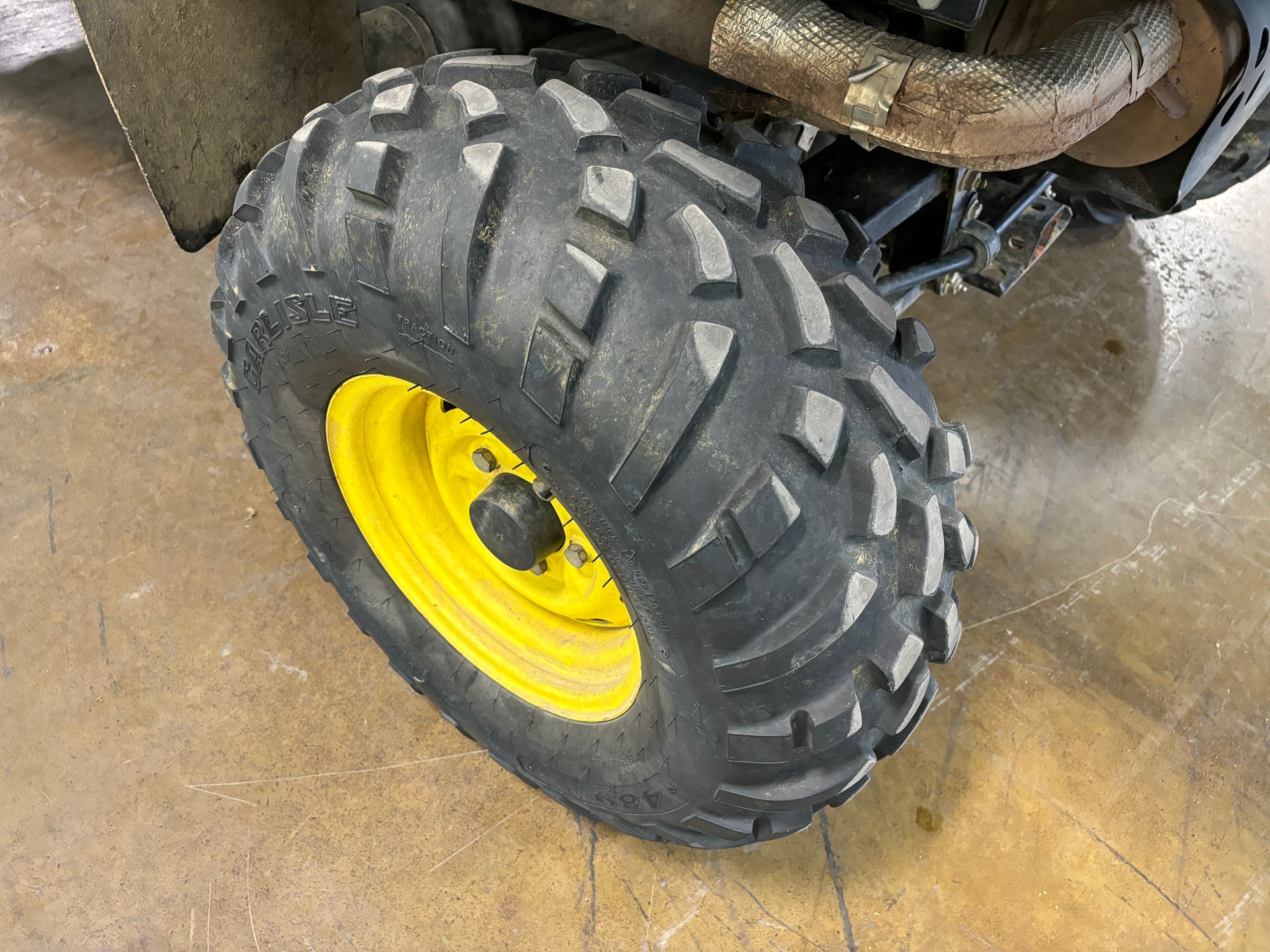 Close-up of a black tire with a yellow rim on a utility vehicle, set on a concrete floor.