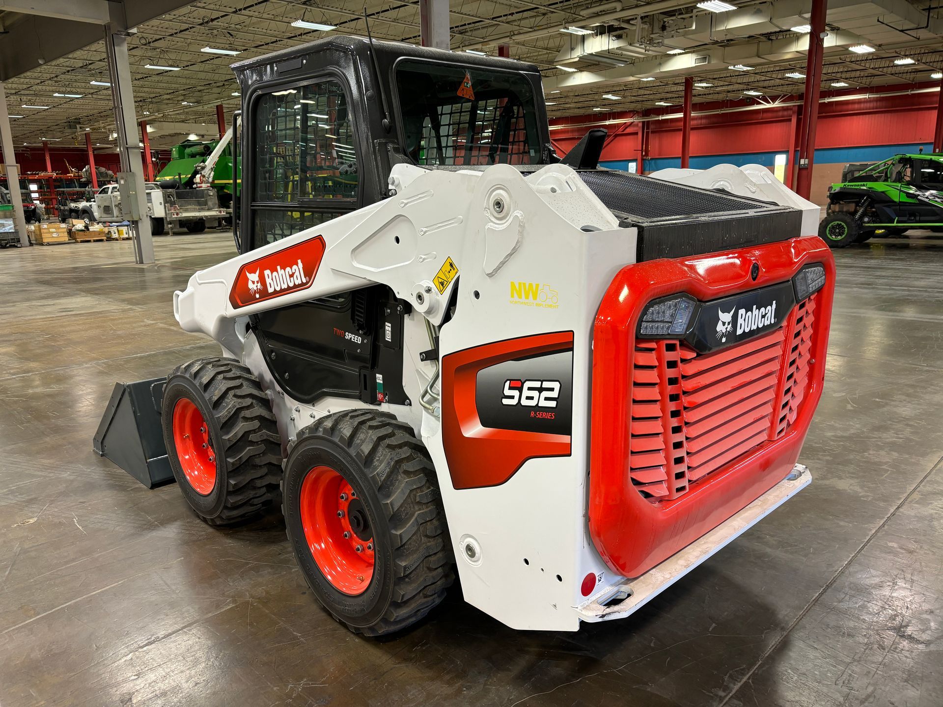 Bobcat S62 skid-steer loader, white and red, parked inside a warehouse.