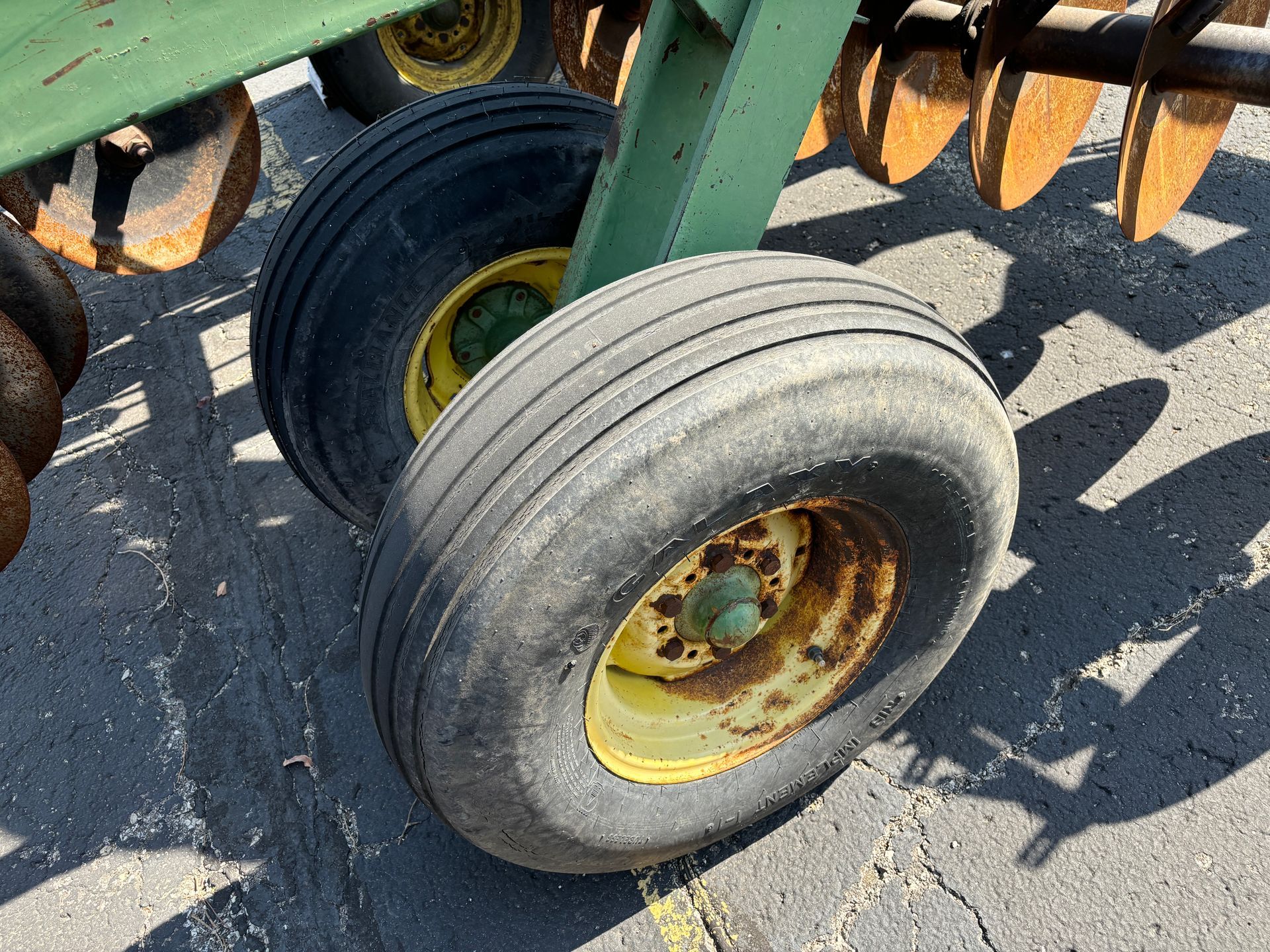 Two large black tires with yellow rims on a John Deere farm implement.