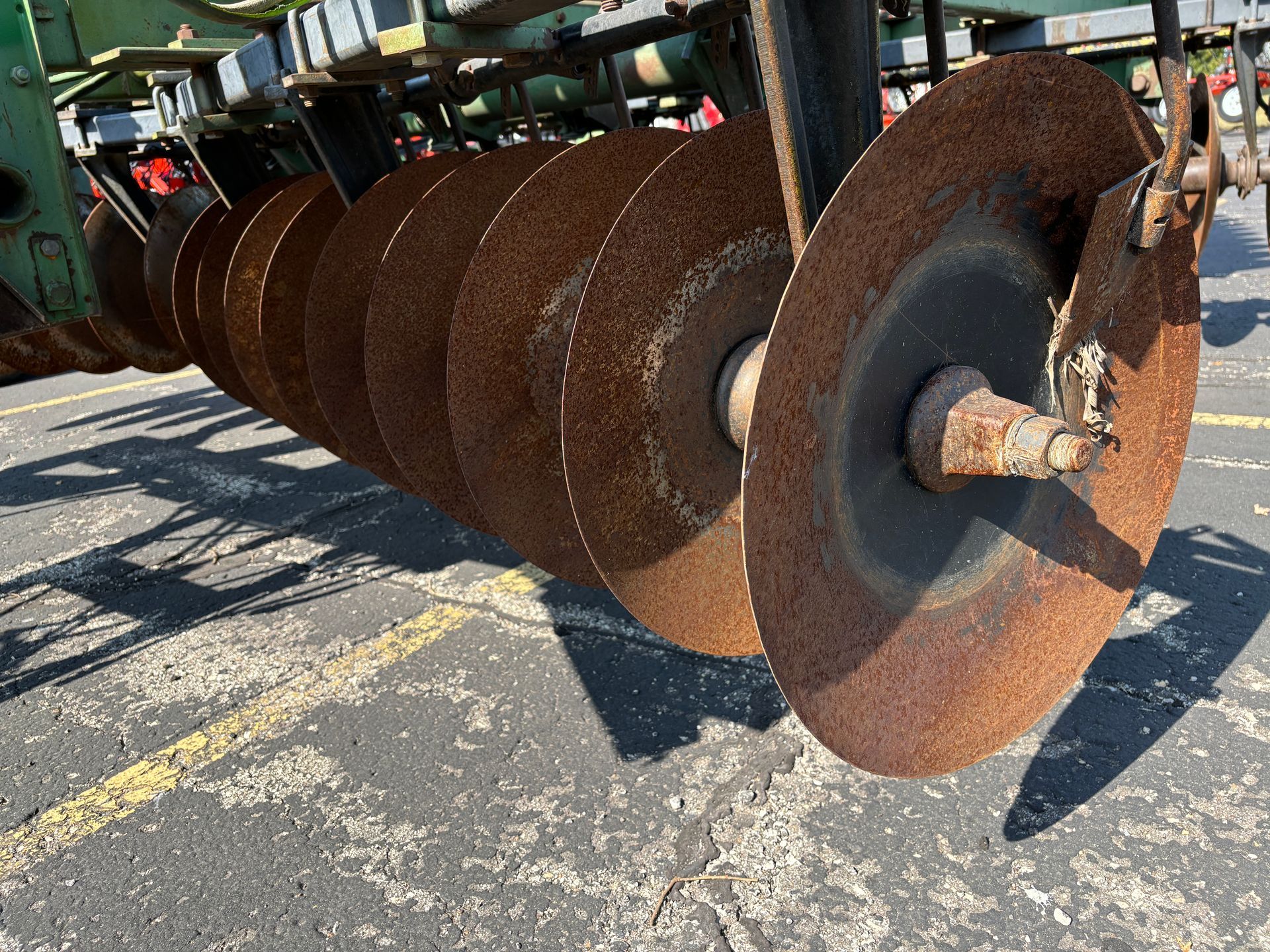 Close-up of rusty agricultural disc harrow blades in an outdoor setting.