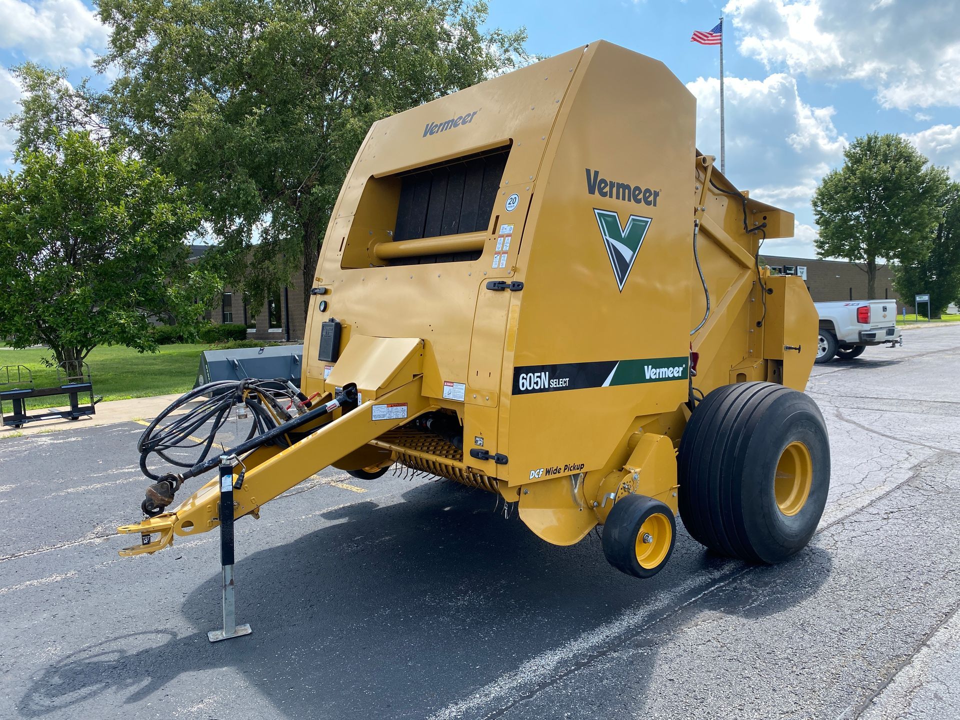 Yellow Vermeer baler on pavement, preparing hay bales.