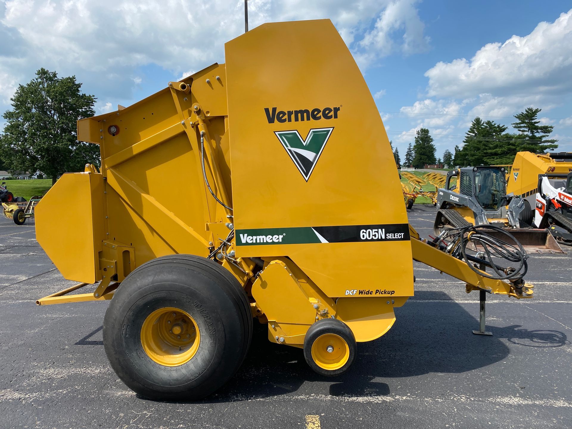 Yellow Vermeer round baler with large tires, in a parking lot.