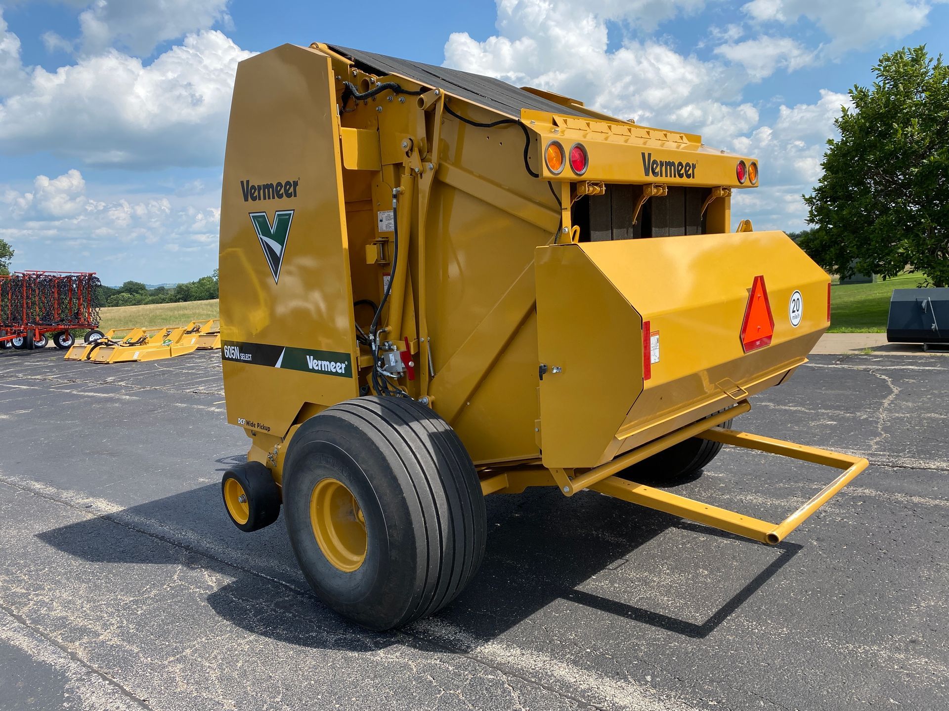 Yellow Vermeer hay baler with black tires on a sunny day.