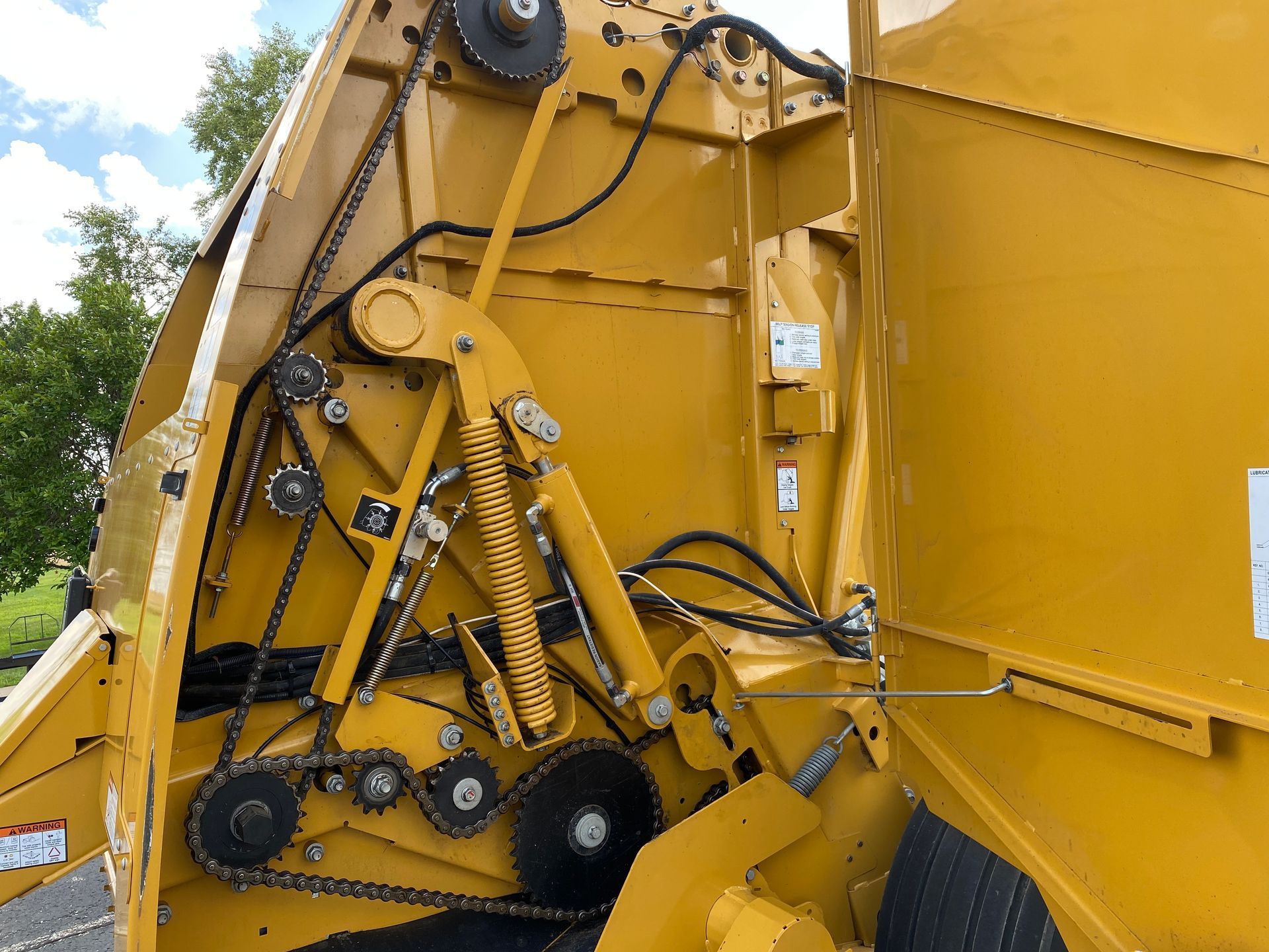 Yellow baler interior with belts, chains, and mechanical components.
