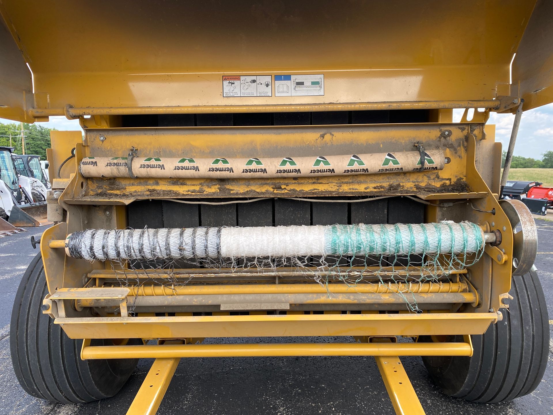 Yellow hay baler with rolls of twine, ready for use.