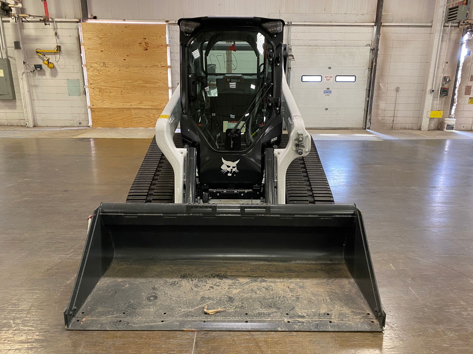 Bobcat compact track loader with bucket, inside a warehouse.