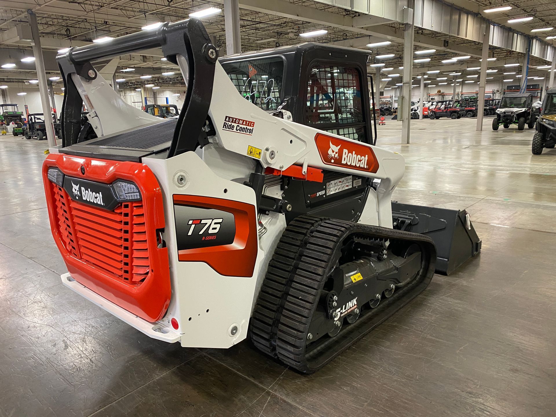 White and orange Bobcat T76 compact track loader inside a large building.