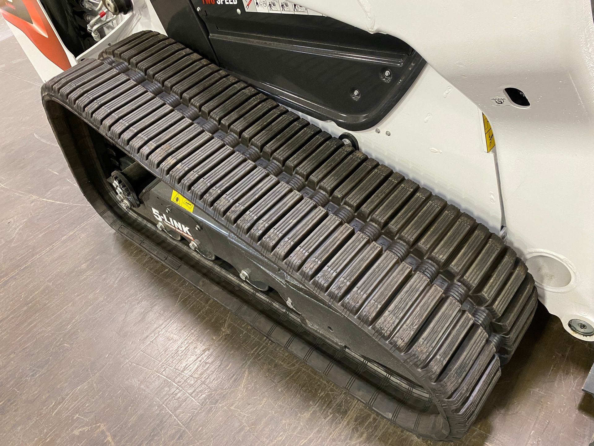 Close-up of a track on a white and gray construction machine, showing treads and metal components.
