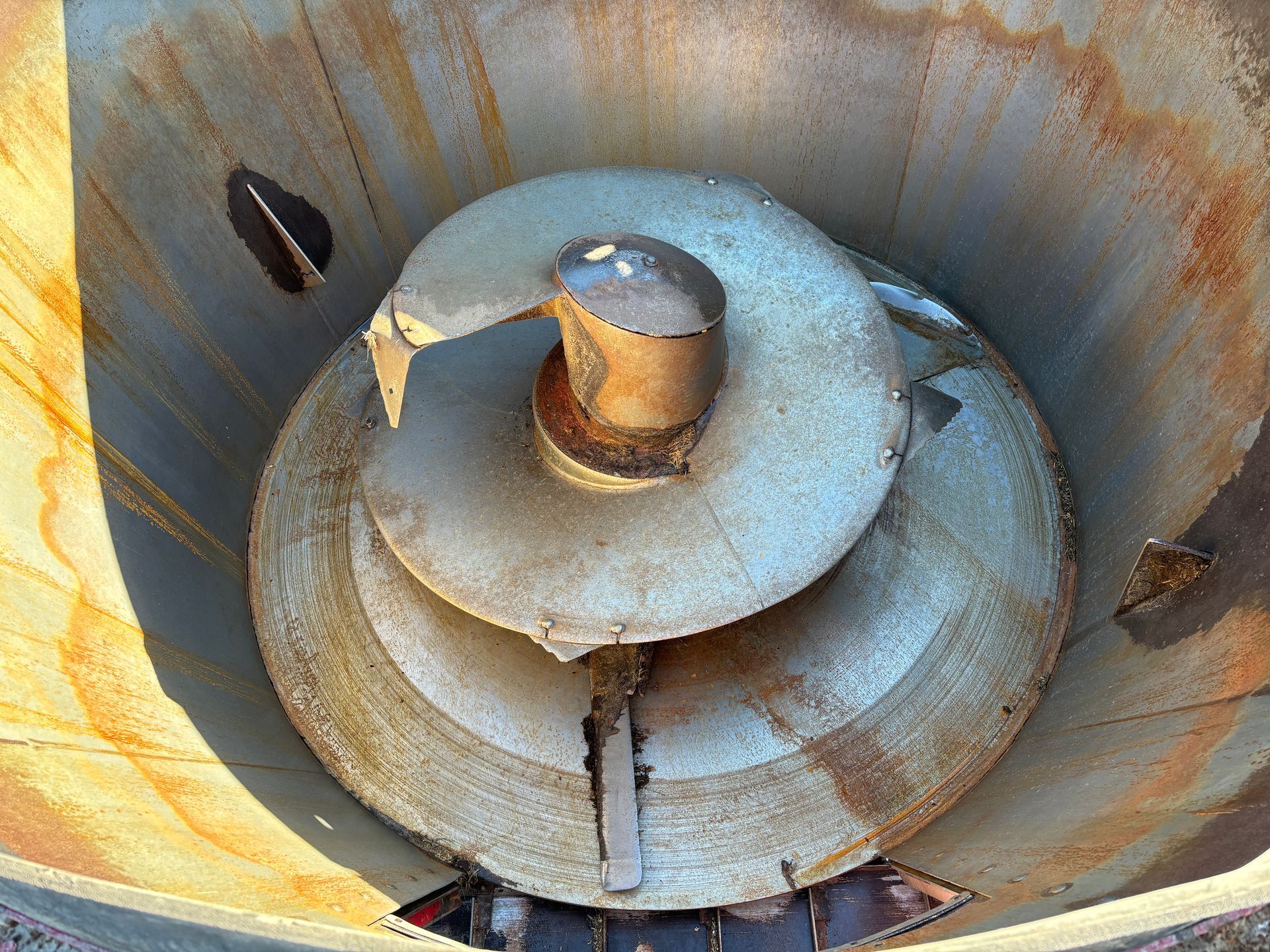 Inside view of a mixer wagon with a rotating spiral blade and central post.