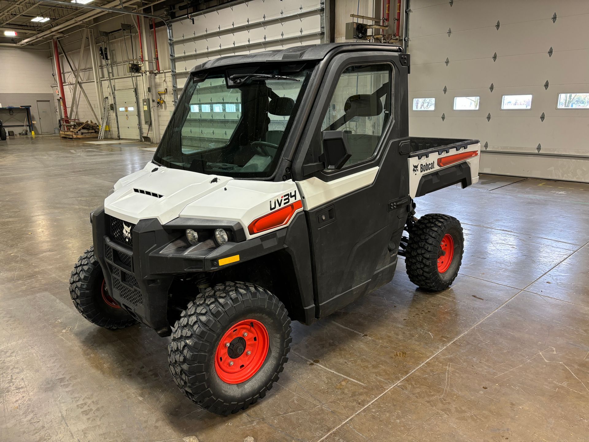 White and black Bobcat utility vehicle with red wheels in a garage setting.