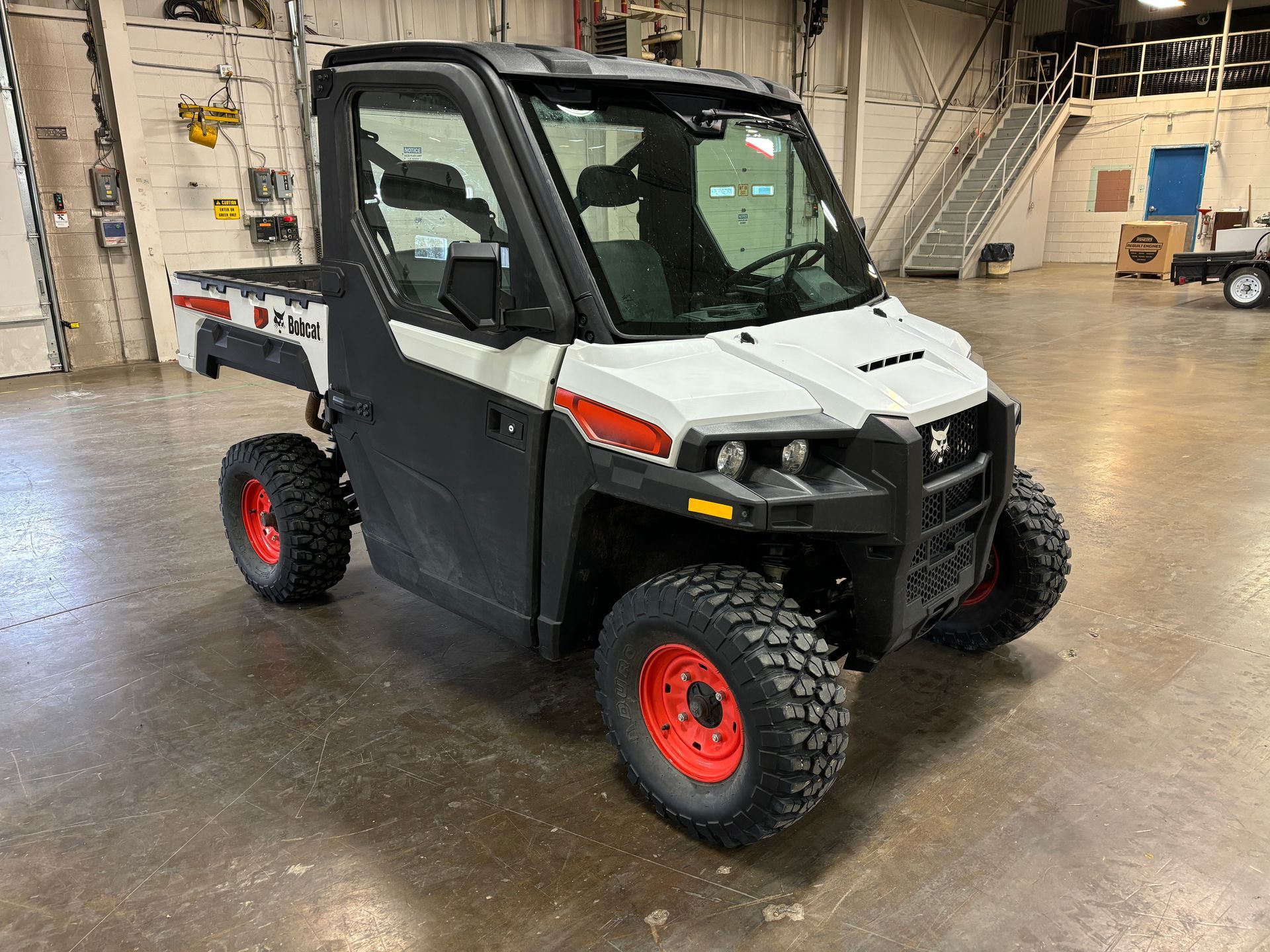 White and black utility vehicle with red wheels in a warehouse.