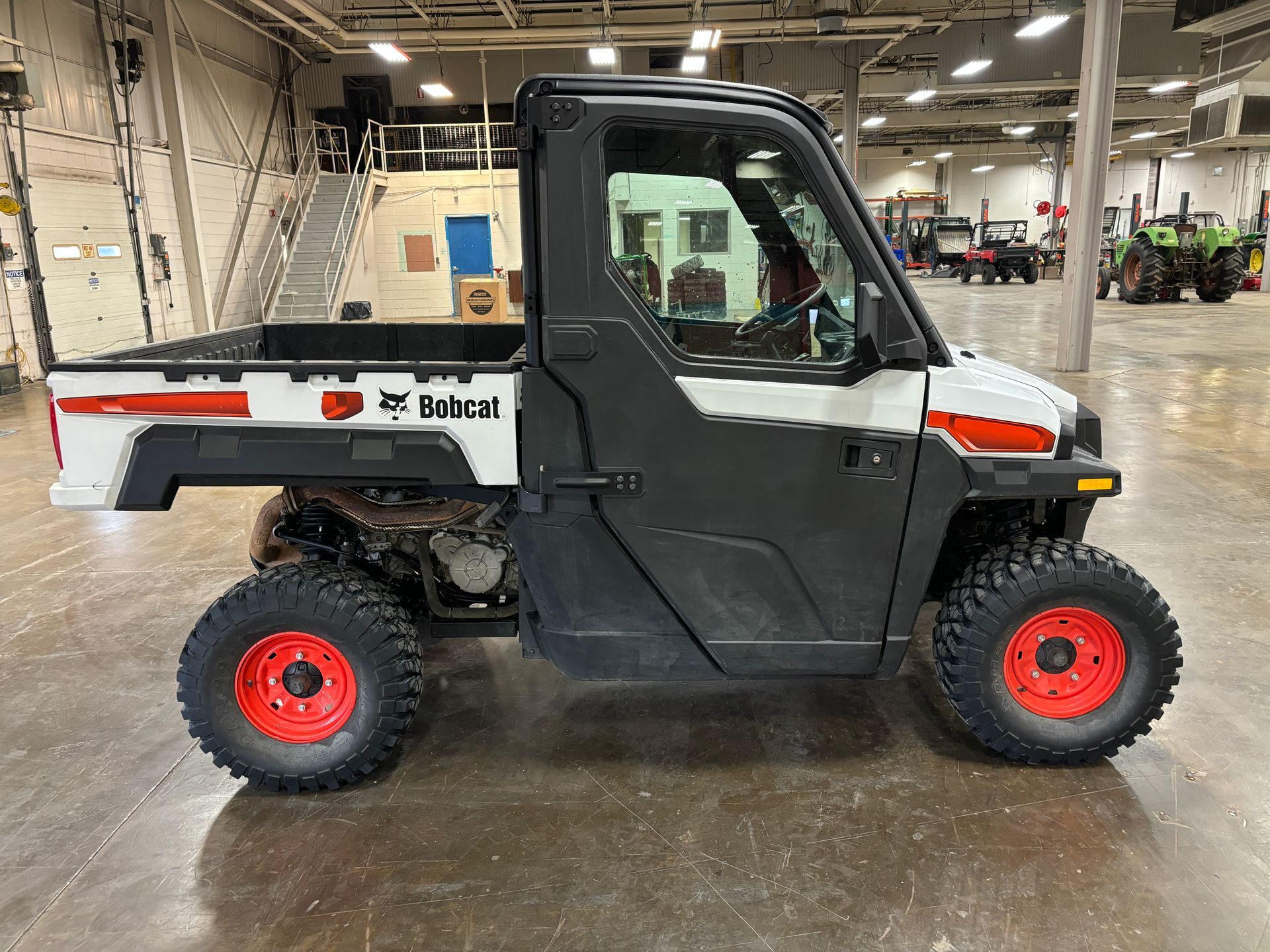 Bobcat utility vehicle with black and white paint, red wheels, indoors.