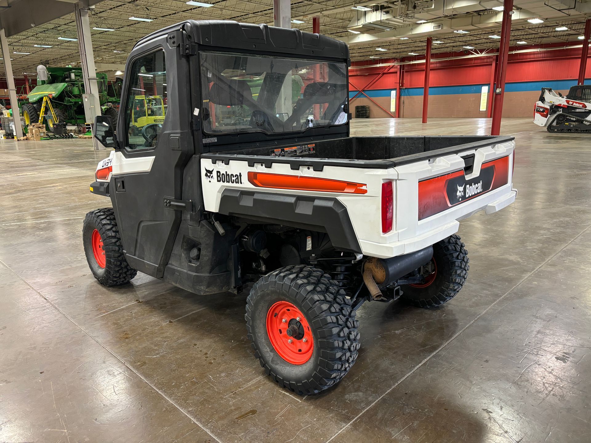 White Bobcat utility vehicle with orange accents and wheels, outdoors.