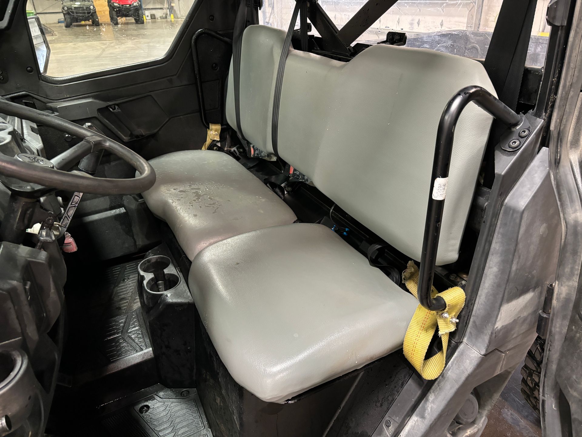 Interior of a UTV with gray seats and a black roll bar.