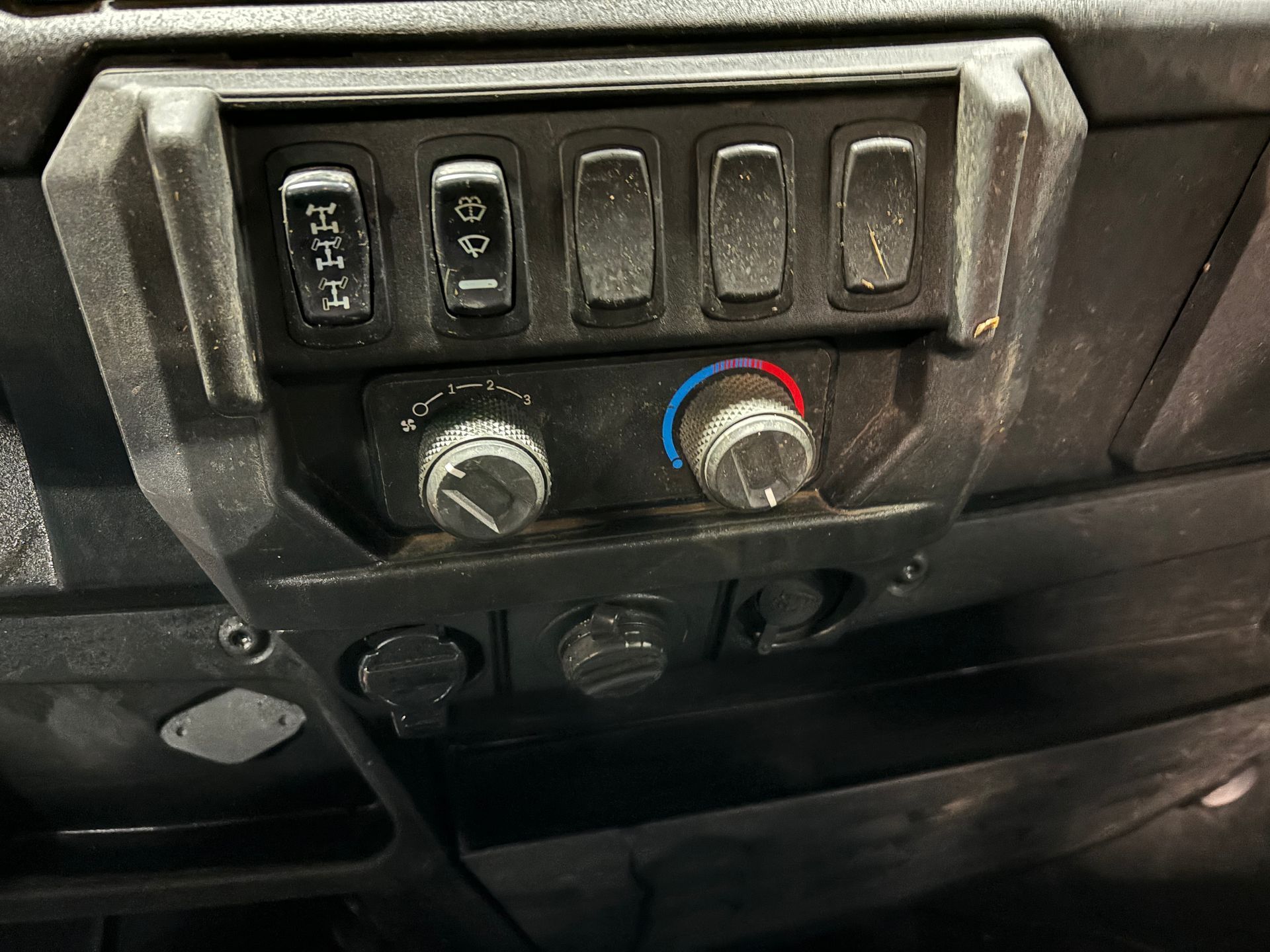 Dashboard controls in a utility vehicle, featuring switches, knobs, and outlets.