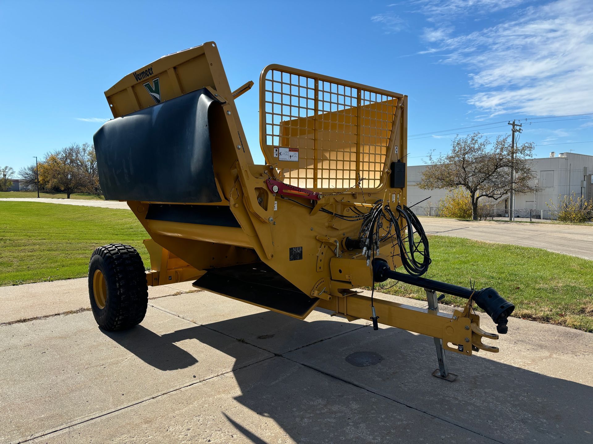 Yellow bale processor on a paved surface, front angled shot.