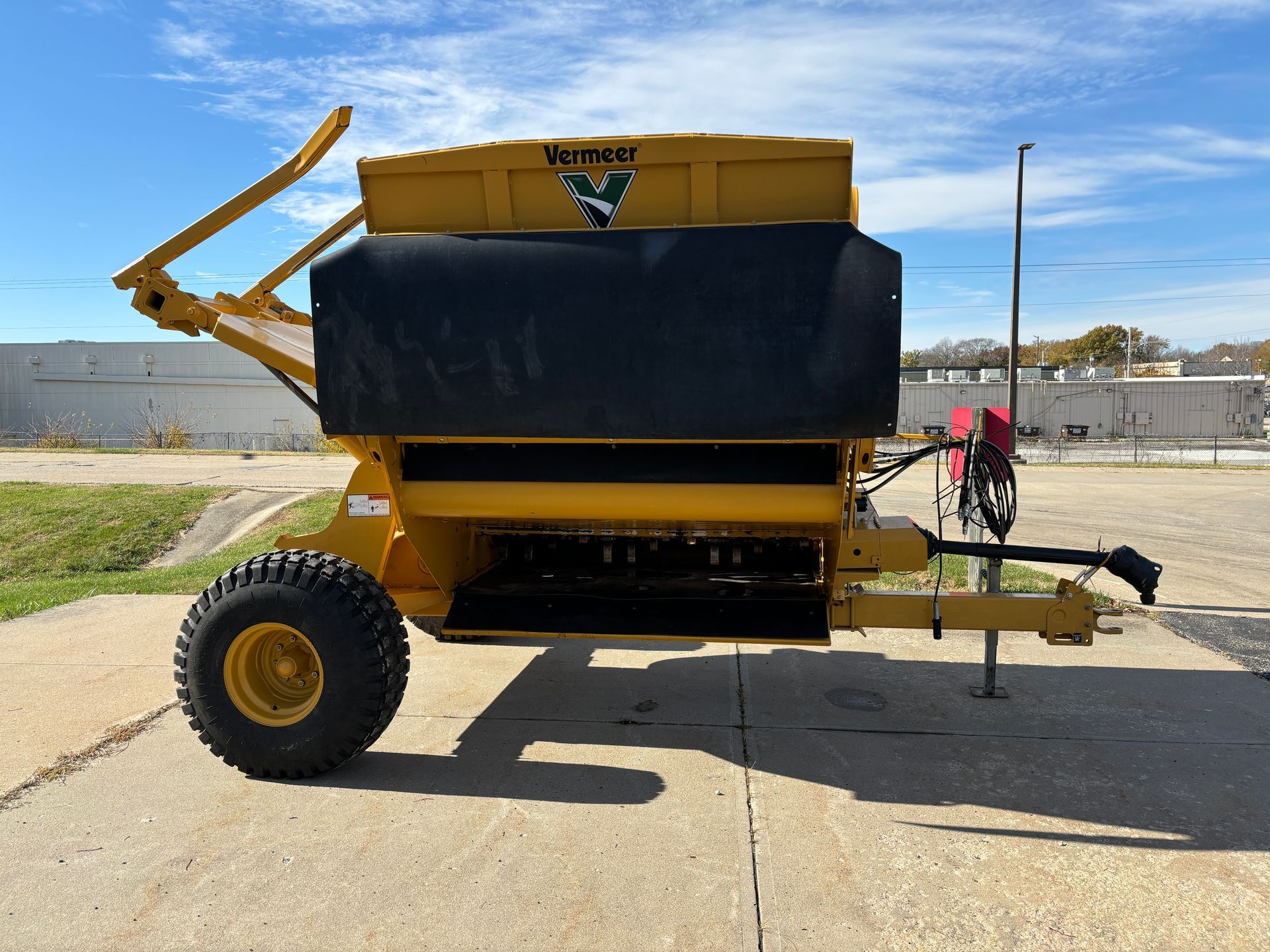 Yellow bale processor on a paved surface, side view shot.