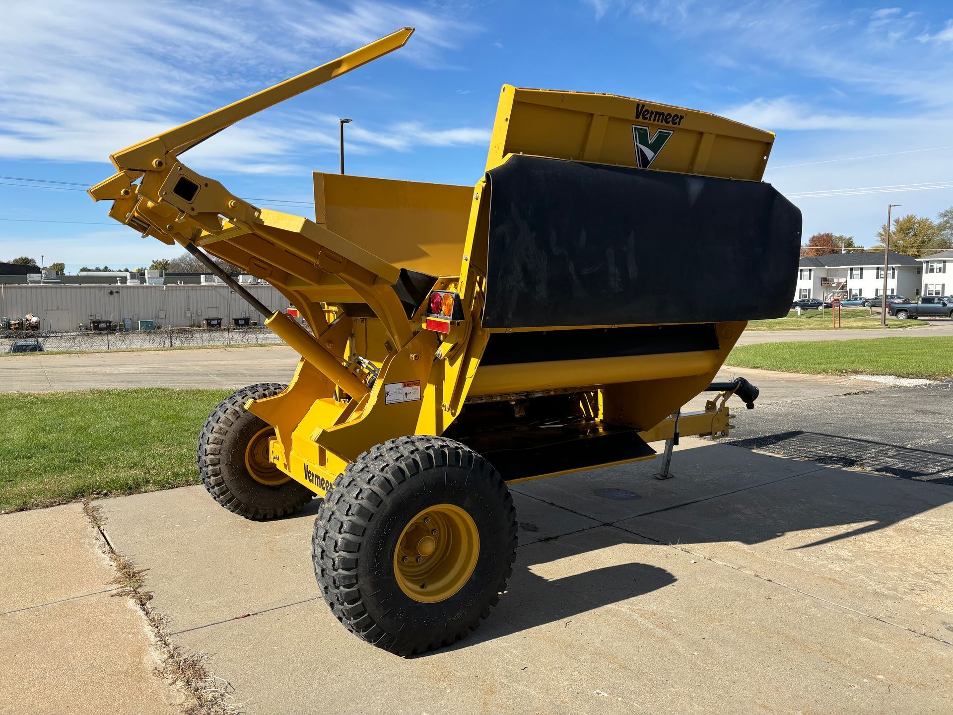 Yellow bale processor on a paved surface, back angled shot.