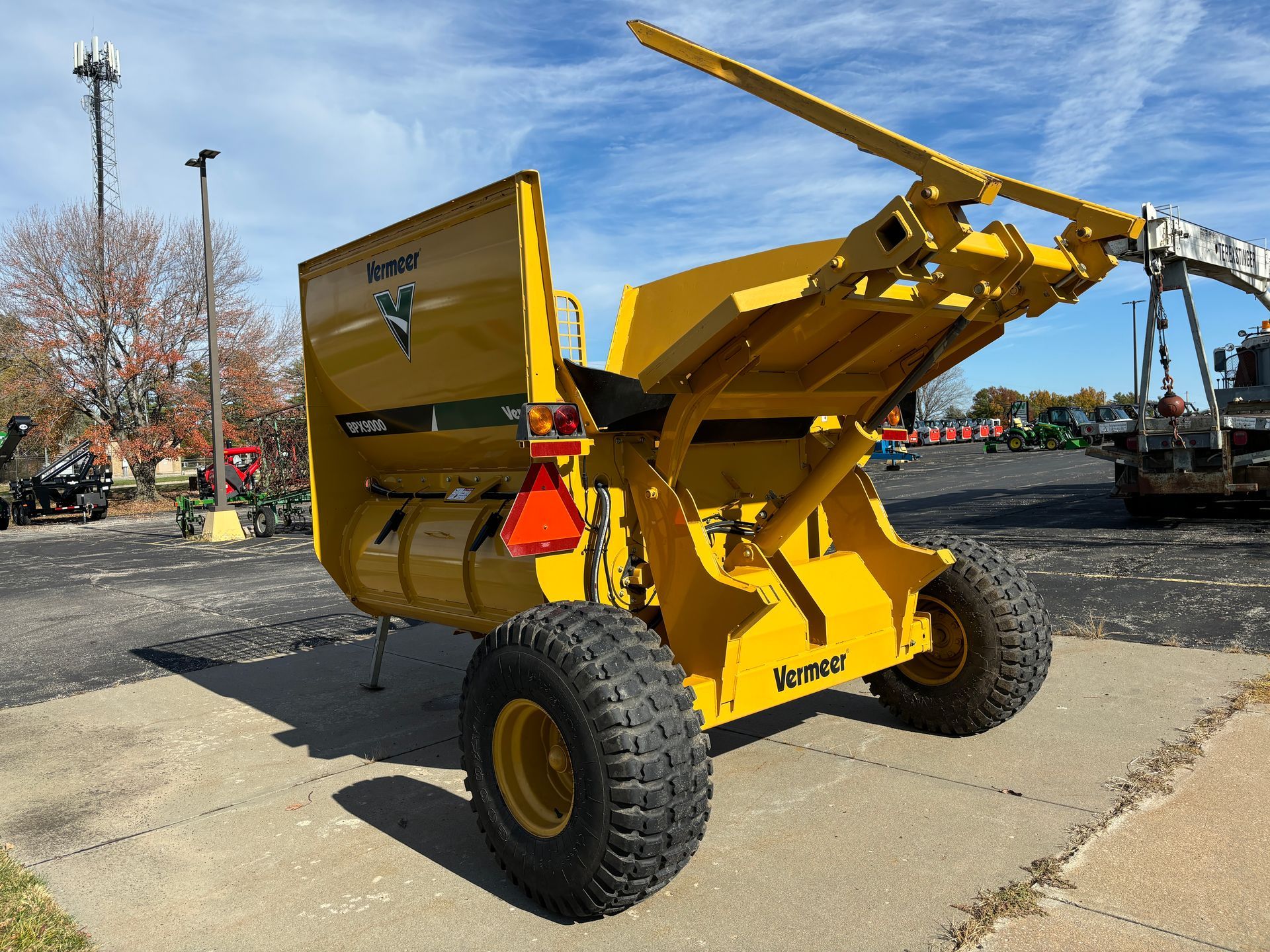 Yellow bale processor on a paved surface, back angled shot.