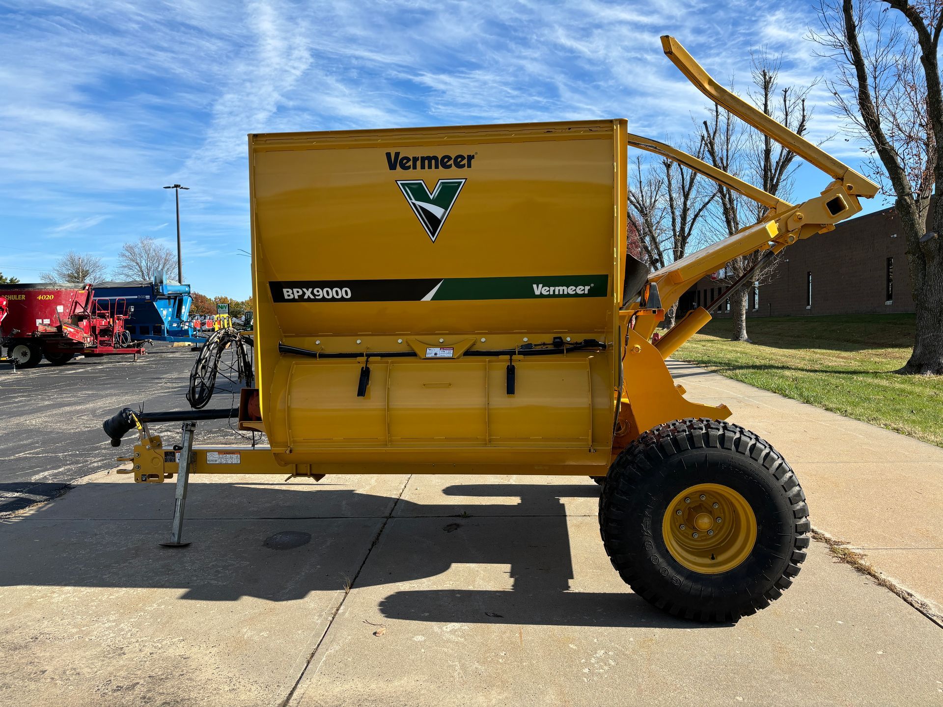 Yellow bale processor on a paved surface, side view shot.