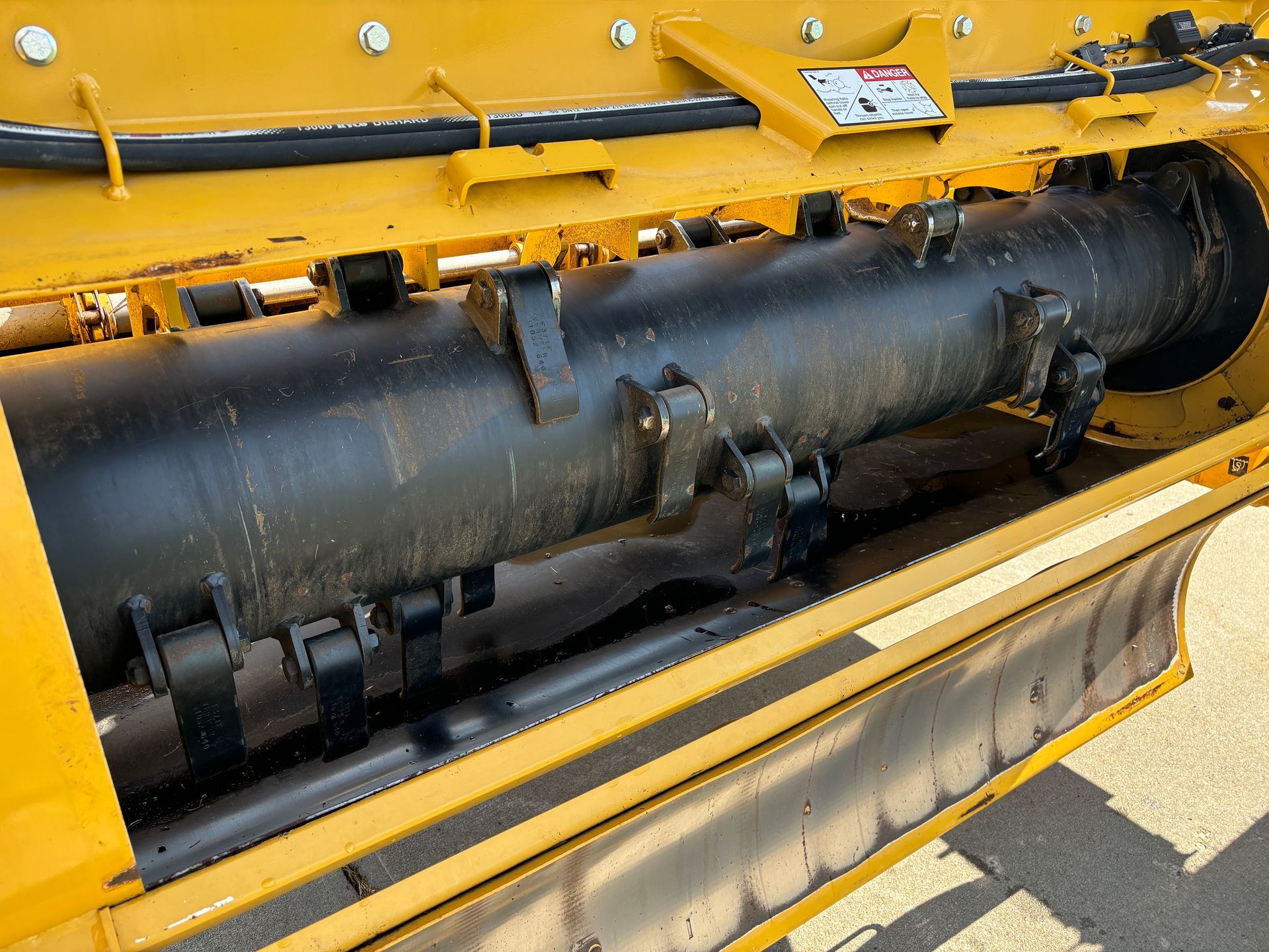 Close-up of a yellow and black bale processor machine with rotating blades