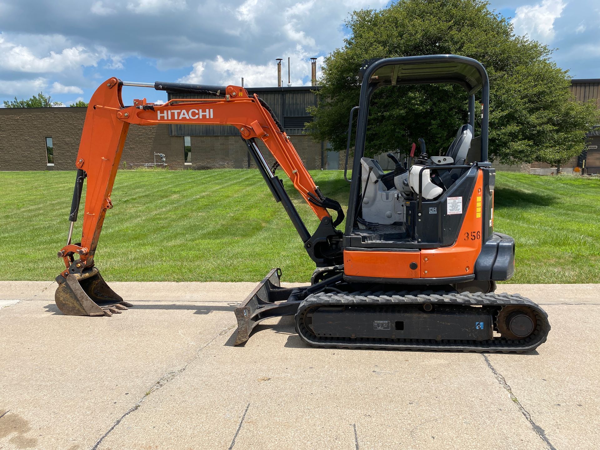 Orange and black Hitachi mini excavator parked on pavement.