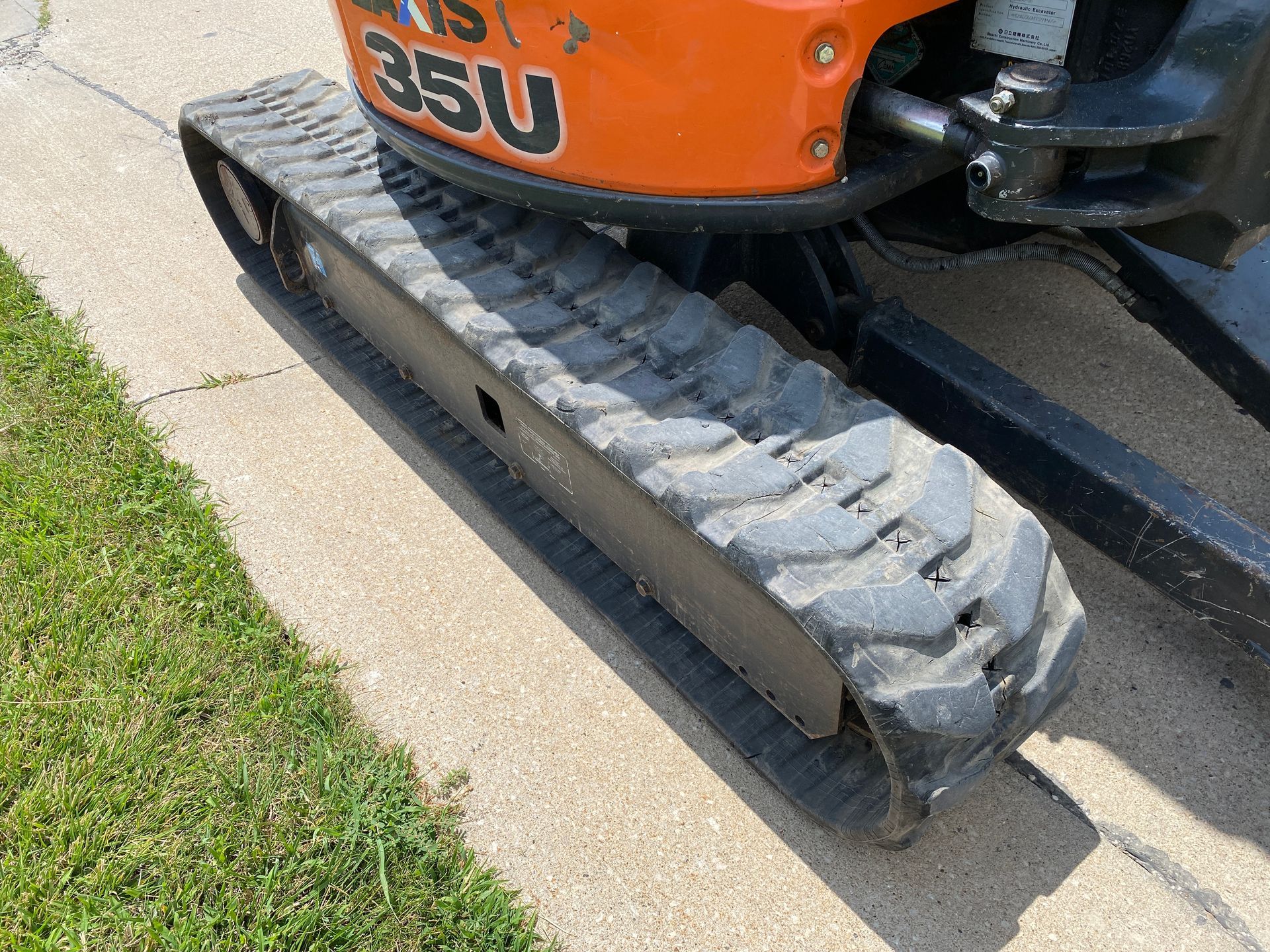 Orange and black mini excavator track on concrete.